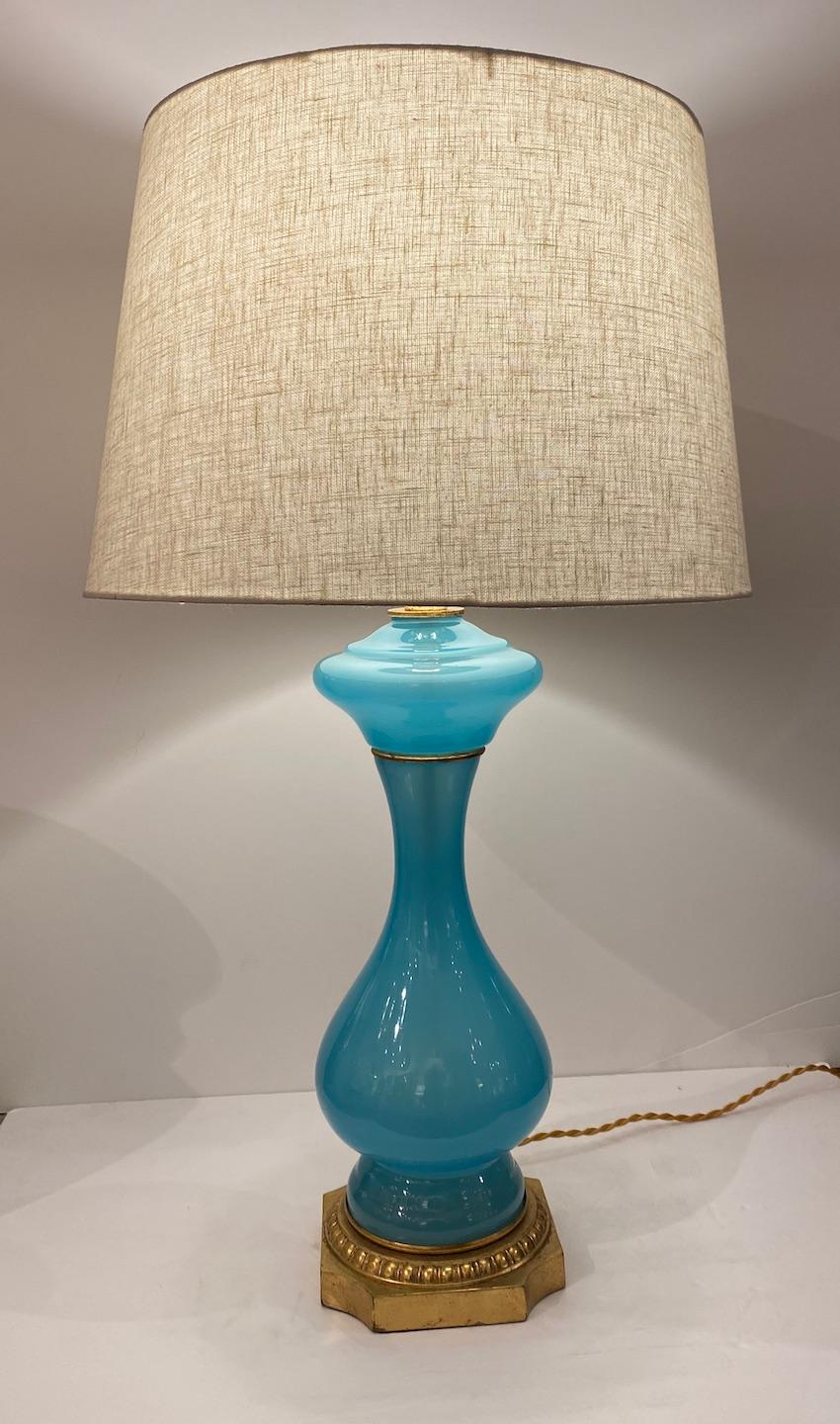 Magnifique lampe en verre opalin bleu aqua avec bandeau et base en métal doré.  Abat-jour en lin blanc cassé.  Câblé pour les États-Unis.