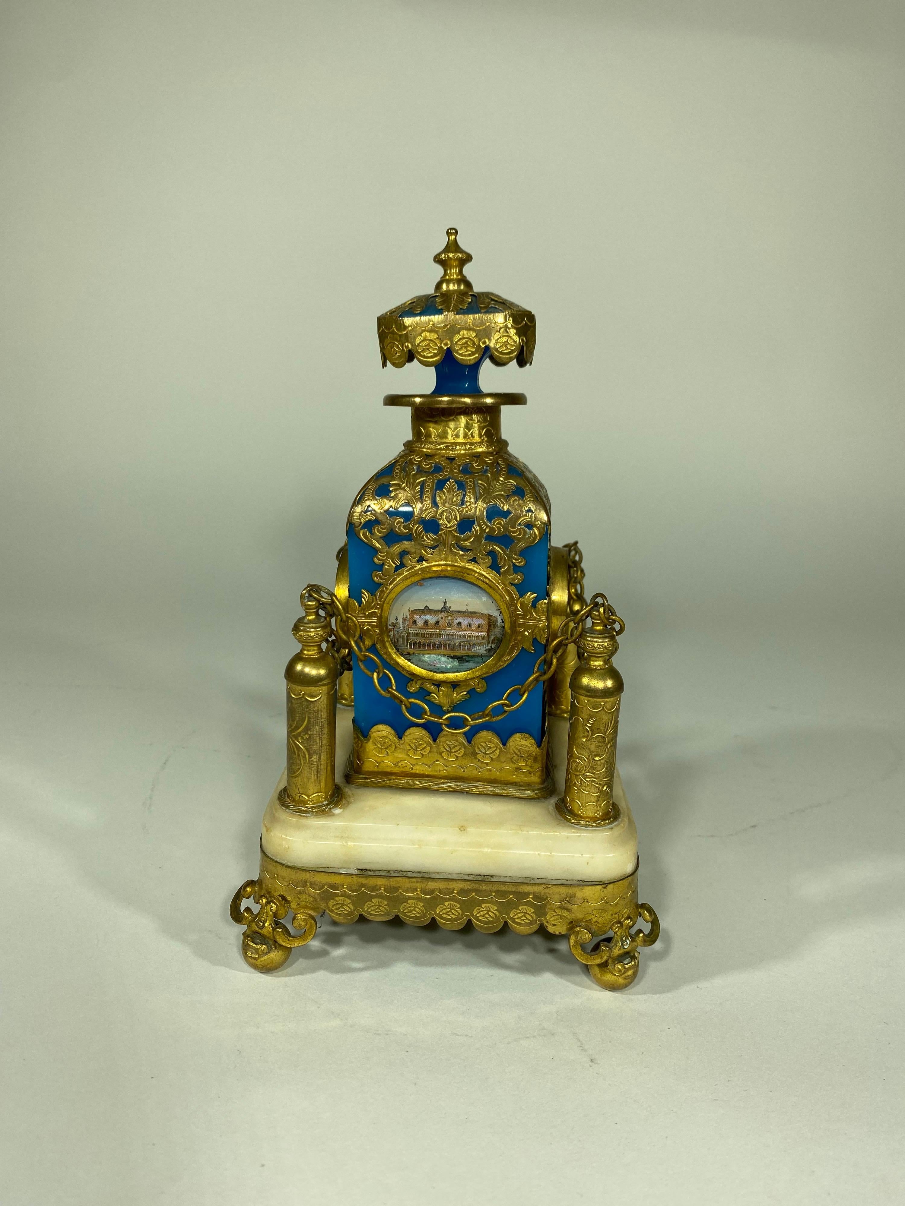 Rare opaline scent (Perfume) bottle with gilt bronze mounts and four medallions with mother of pearl enhanced lithographs in ovals on each side of bottle portraying historical sites. Bottle is mounted on a gilt Bronze and Marble stand with chains.