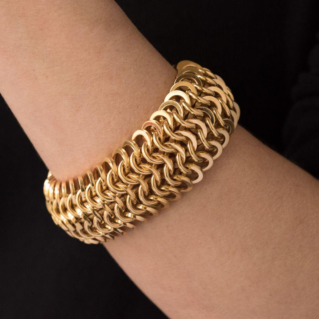 Bracelet in Yellow gold 18K rhino head hallmark.
Supple and rounded, this wide bracelet is formed of a mesh of intertwined gold rings. The clasp is a 2.8 safety ratchet. 
Total length: 23 cm, width: 2.9 cm.
Weight: 97.8 g approx.
Authentic vintage
