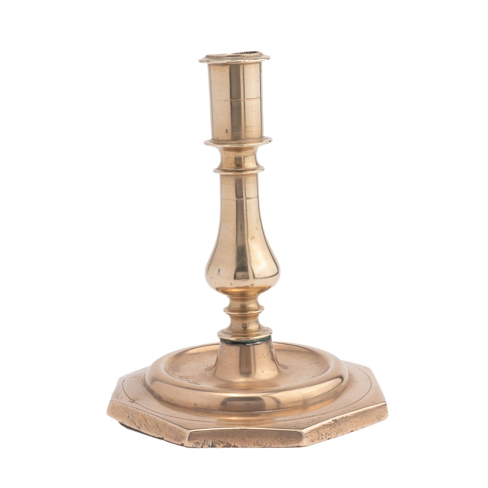 Solid cast bell metal brass candlestick with candle cup and beaded rim on a classic baluster, threaded to a circular rimmed drip pan on a raised octagonal base. The candle cup is drilled with an 'economy' boring for the removal of the candle stub.