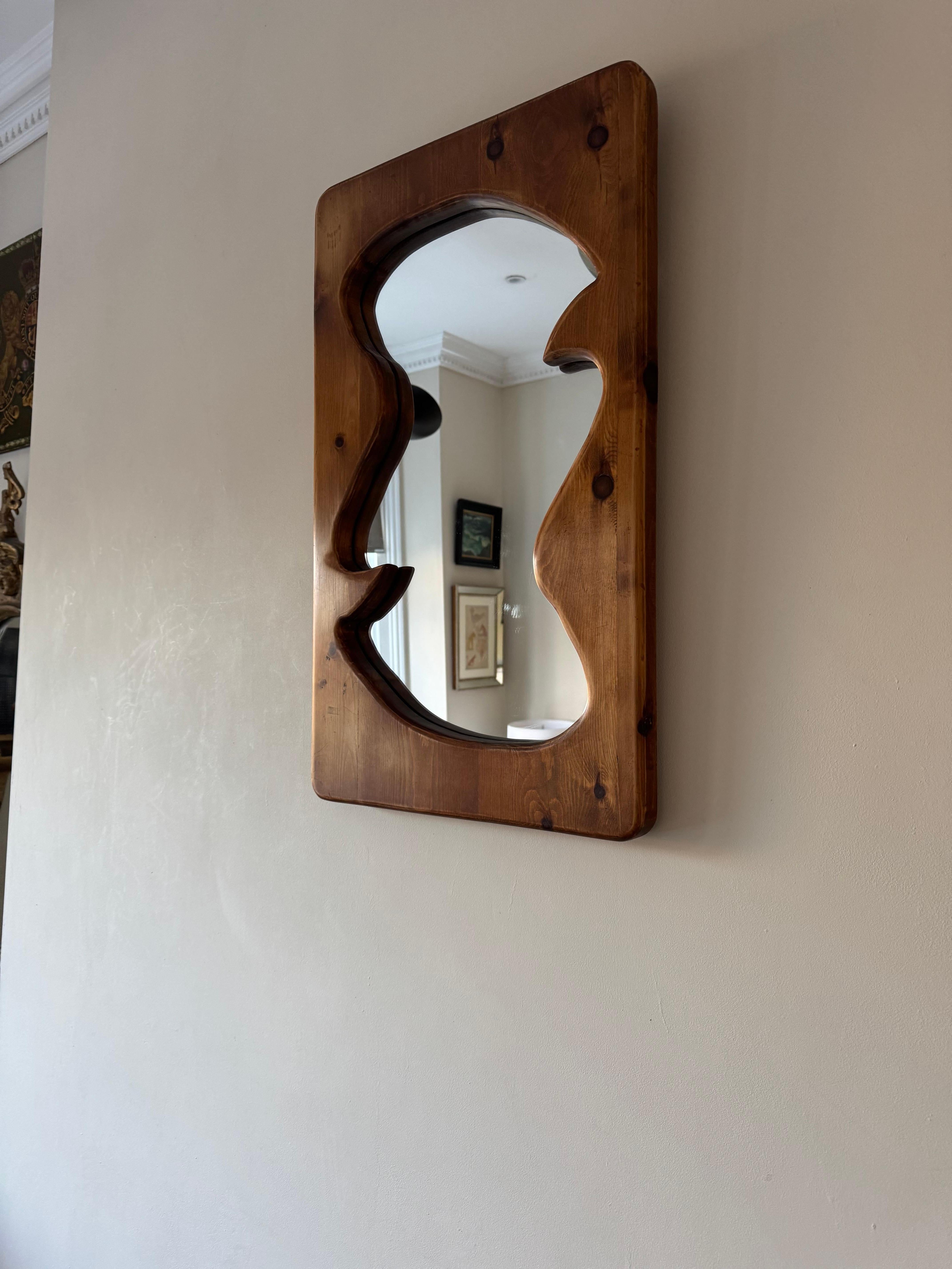 A hand carved pine framed mirror of organic form. 