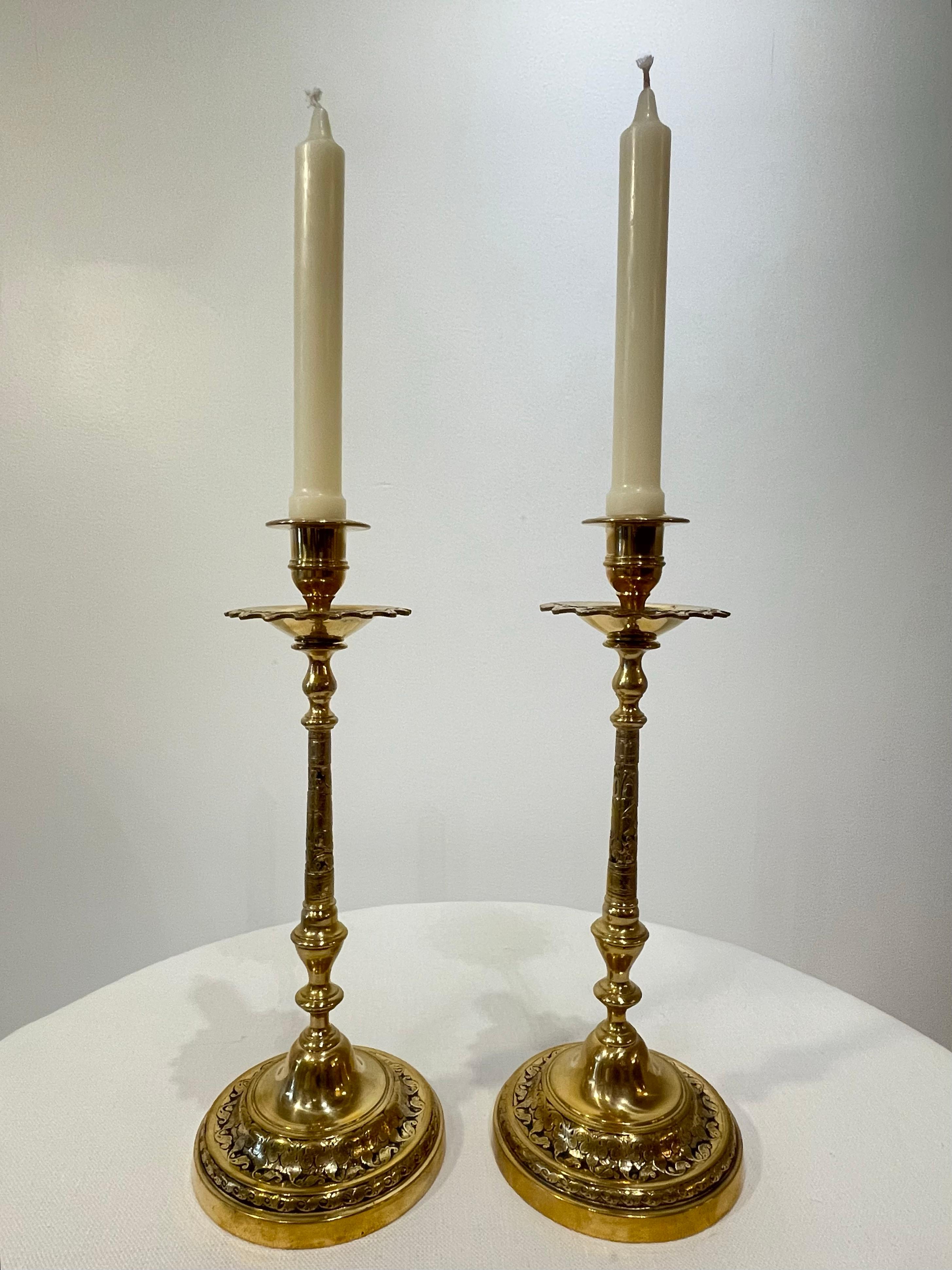 Late 19th century pair of brass candlesticks with exotic style detail. In the Ottoman tastes made popular during the 1880s, these tall candlesticks are both glamorous in proportion and strong in their design. 