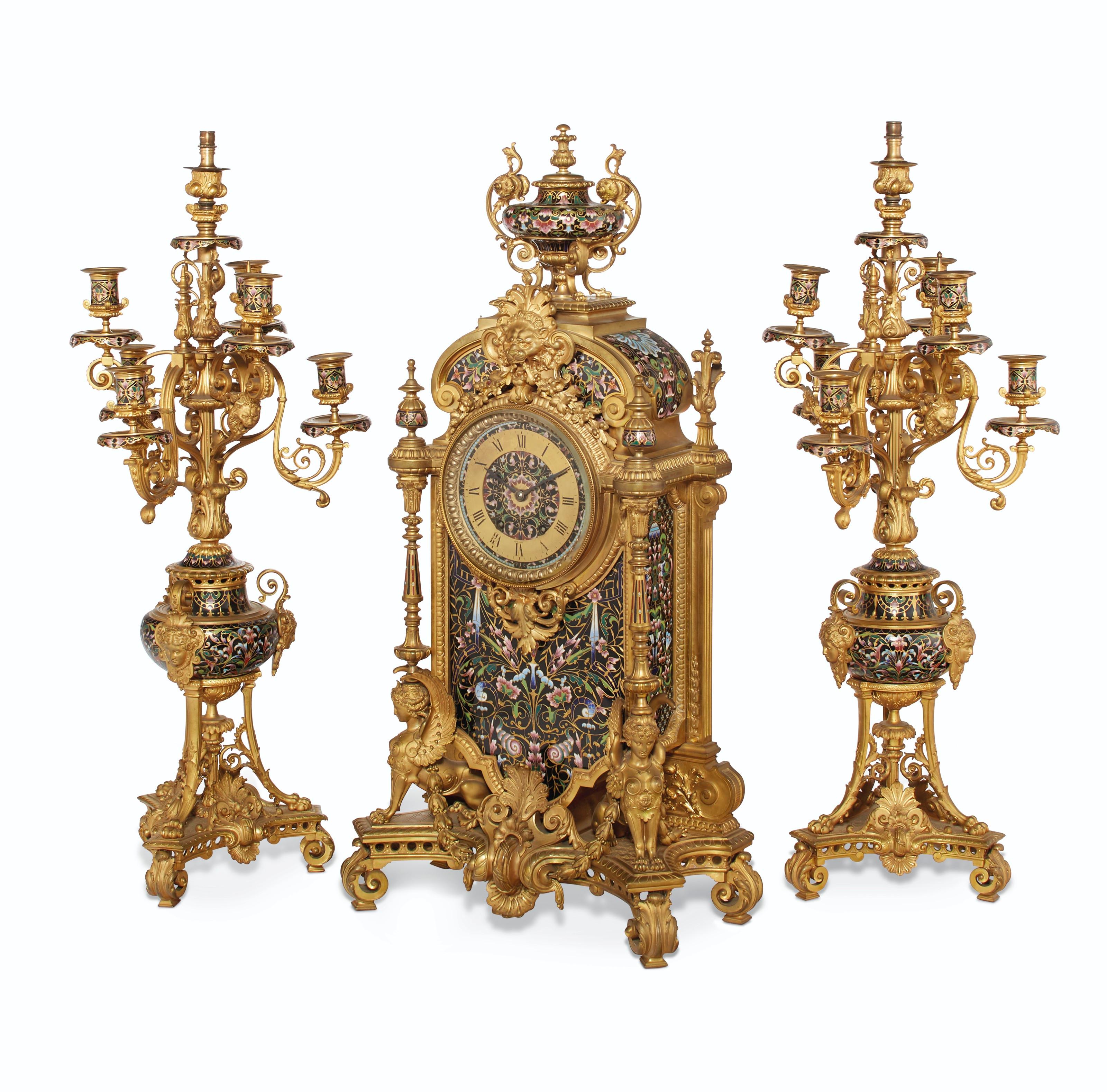 A Large French Ormolu and Champlevé Enamel Three-piece Clock Garniture

Late 19th Century
Comprising a clock and a pair of seven-light candelabra, all decorated throughout with densely enameled flowers and foliage, the clock supported by a pair