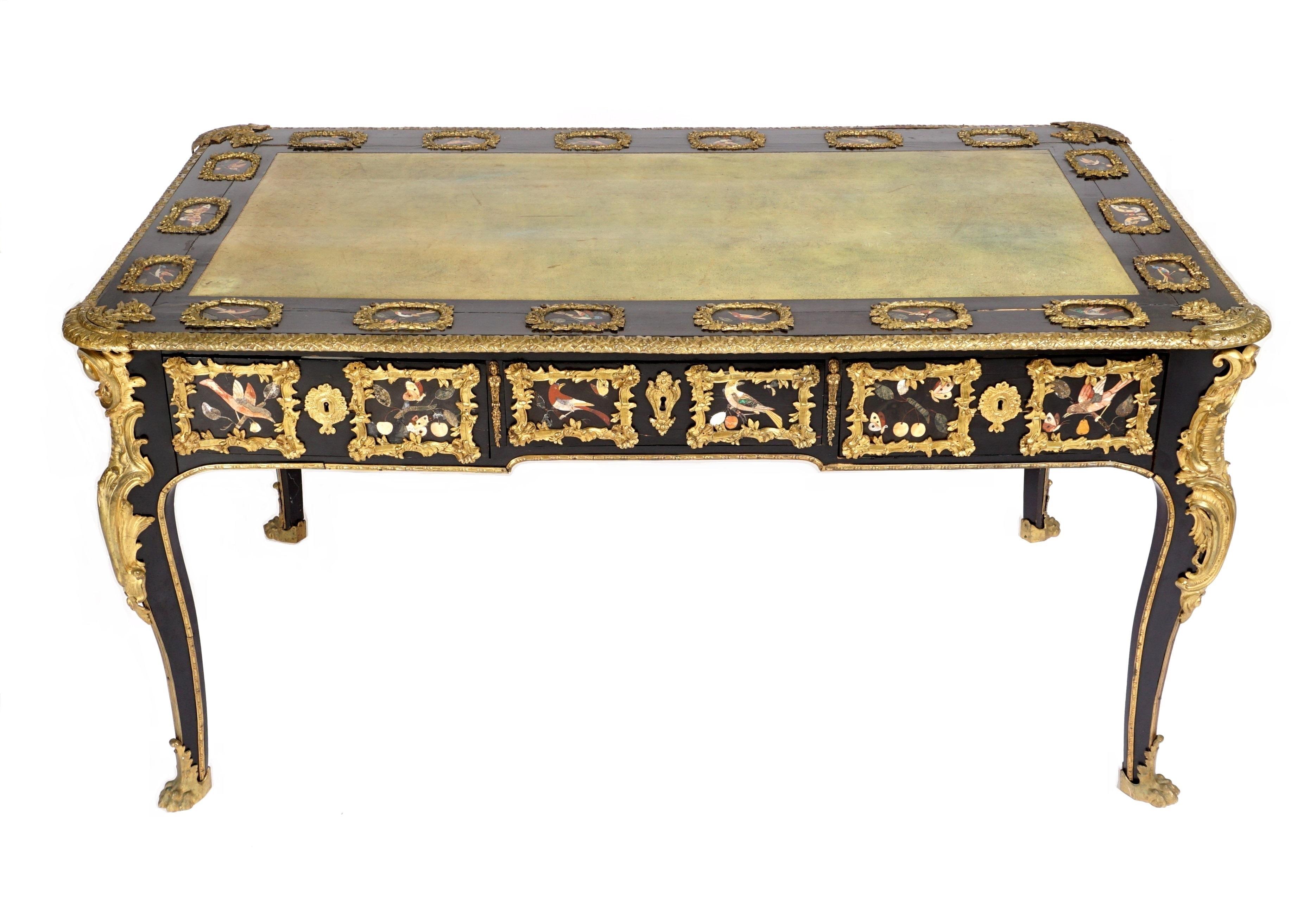 French Ormolu and Pietra Dura Mounted Ebonized Bureau Plat.
French bureau plat circa 1860 with 36 ormolu bronze framed pietra dura plaques featuring birds and butterflies.  Three drawers with green leather top and ormolu bronze lion paw feet.
