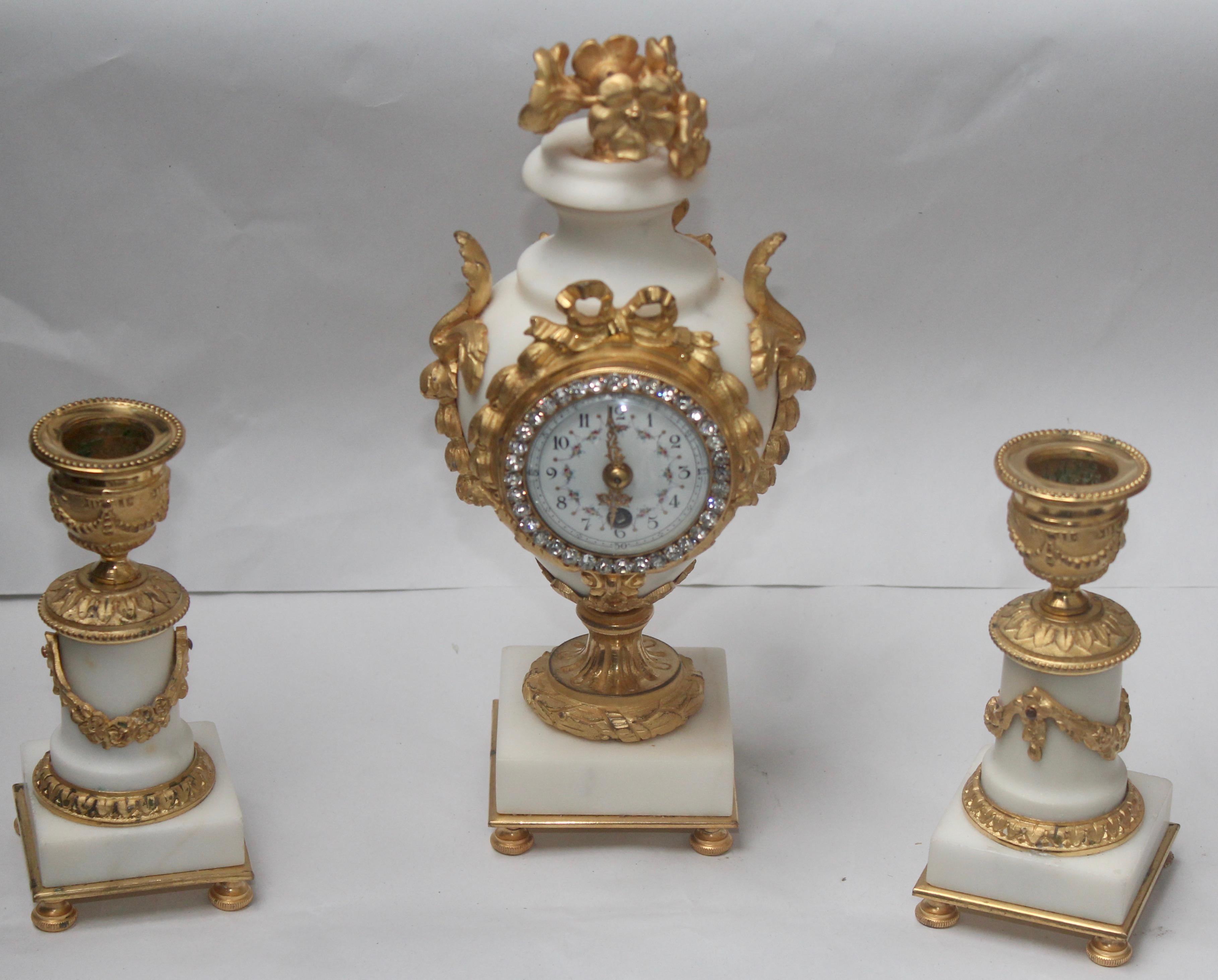 An Exquisive 19th century French ormolu and white marble three-piece Clock Garniture
The central clock is shaped from white marble as a vase, holding gilt bronze flowers and mounted all over with leaves and swags, the dial in polychromed porcelain