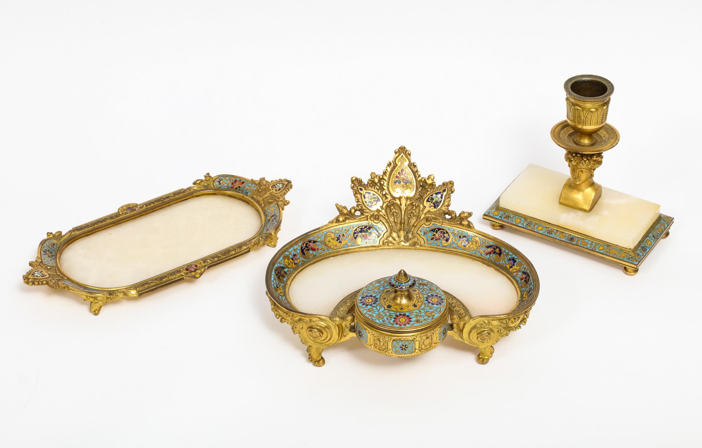 French ormolu bronze, onyx, and champlevé cloisonné enamel three-piece desk set, comprising of an inkwell / encrier, a platter / tray, and a candlestick with a female bust,

circa 1880.

Very fine quality ormolu and enamel. An original set,