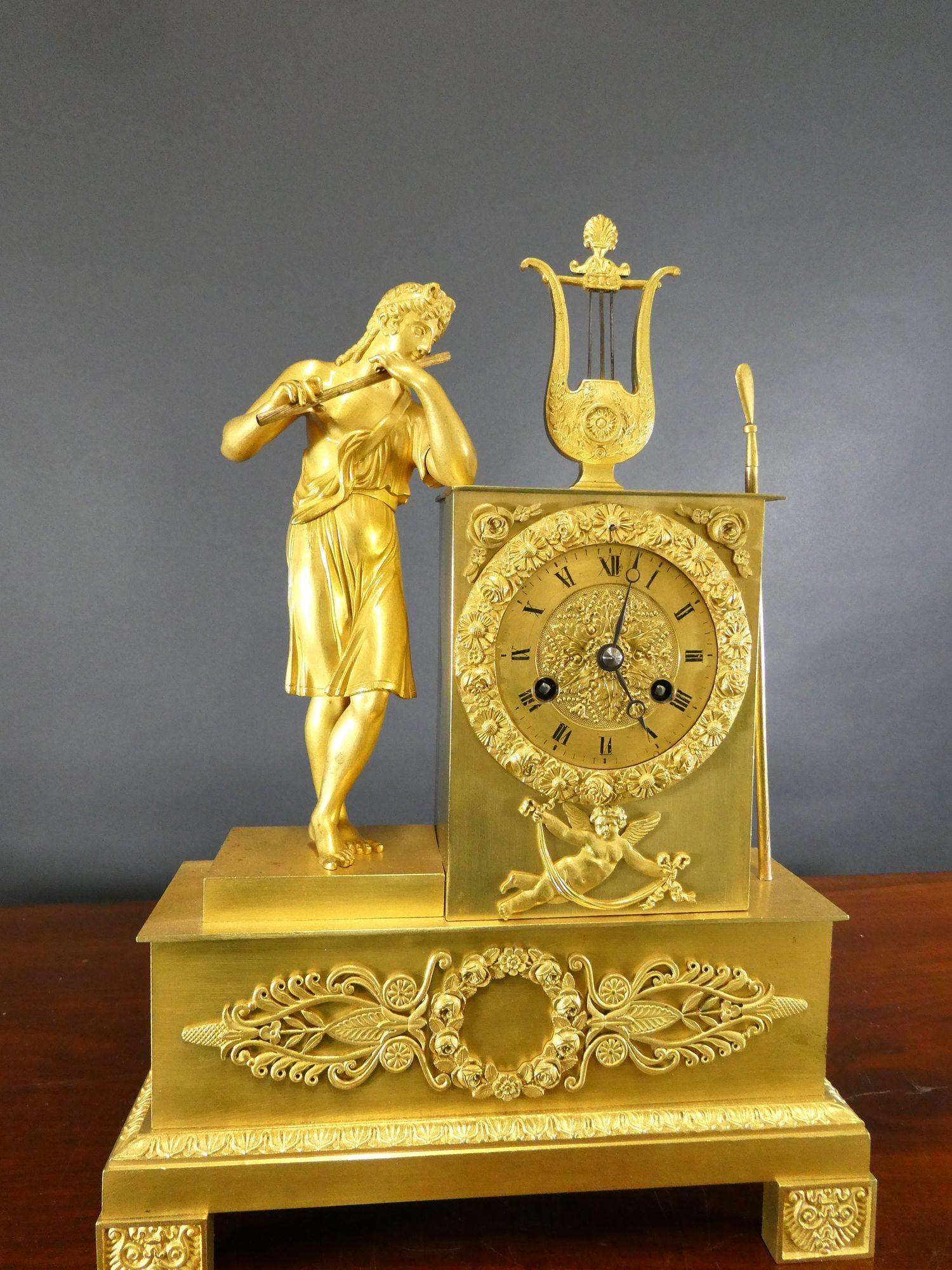 French Ormolu Mantel Clock
French mantel clock housed in an ormolu case with stepped base and decorated feet, floral, wreath and cherub decoration. To the side of the dial is a classical figure in robes playing the flute, the case surmounted by a
