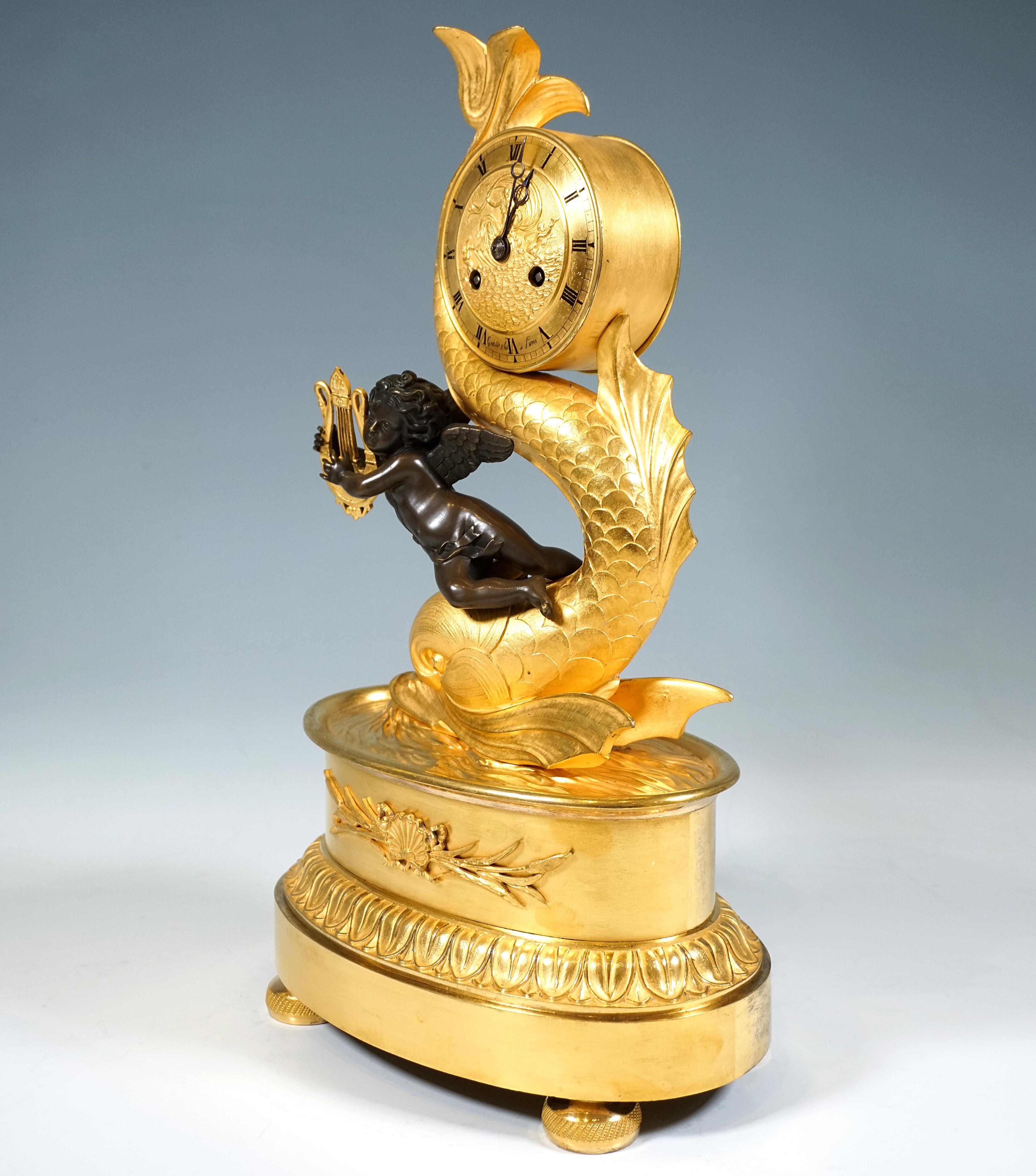 Exquisite fire-gilded Empire bronze mantel clock: Structure in the form of a tall oval, stepped base with lotus leaf relief, standing on four tubular feet with side engraving, with a relief ornament applied to the centre of the front - a Venus shell
