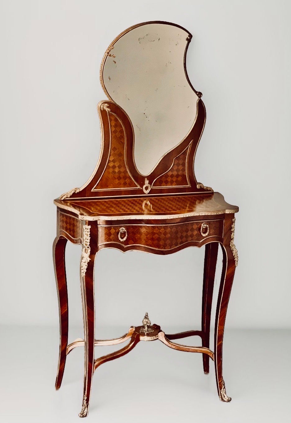 French Louis XV style ormolu-mounted kingwood and satinwood parquetry dressing table or coiffeuse, late 19th century.

Incredibly luxurious petite dressing table inlaid with trellis parquetry and draped in ormolu. It features an ormolu framed and