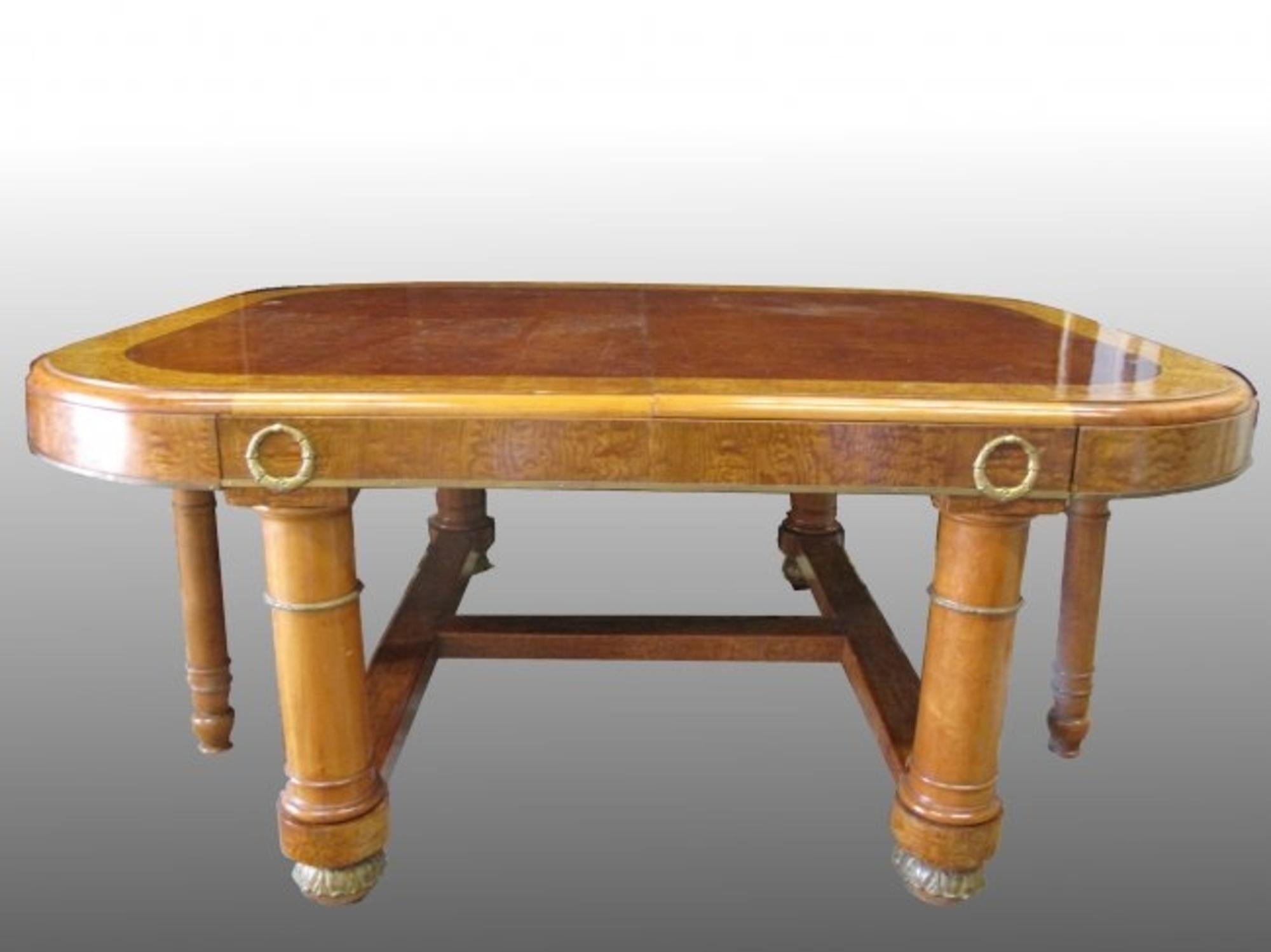 A French ormolu-mounted lacewood and burr maple extending 
Dining table, first quarter of the 20th century.
The rectangular top with rounded corners, the frieze applied with laurel garlands, on heavy cylindrical legs joined by an 'H'-shaped