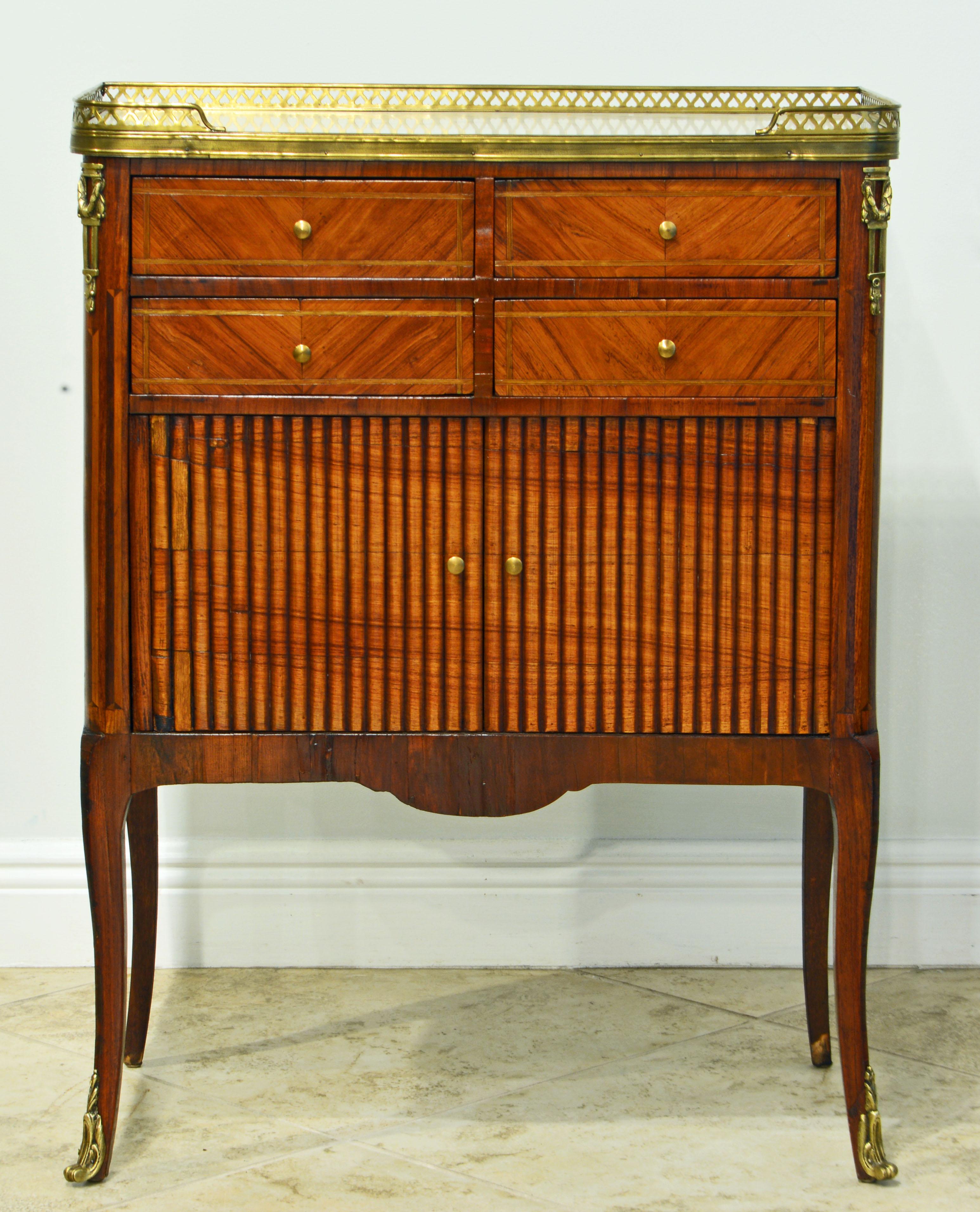 This superior French parquetry commode of beautiful proportions dates to the late 19th century and features a marble top partly surrounded by a reticulated bronze gallery above four drawers and a tambour door cabinet. The corners are accented by