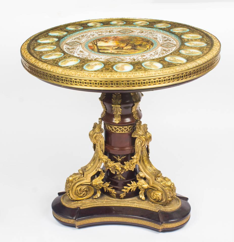 A superb Louis XVI style omolu-mounted gueridon centre table with Sèvres style porcelain plaques, mid-20th century in date. 

The circular top is inset with a central finely painted Sèvres style porcelain plaque depicting a classical landscape