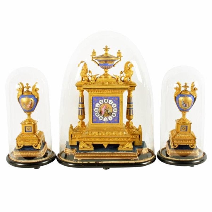 A 19th century Napoleon III French Sévres style ormolu and porcelain three piece clock garniture.

The clock and side ornaments sit on velvet and gilt wood plinths which in turn sit on ebonised plinths that have glass domes.

The clock has an