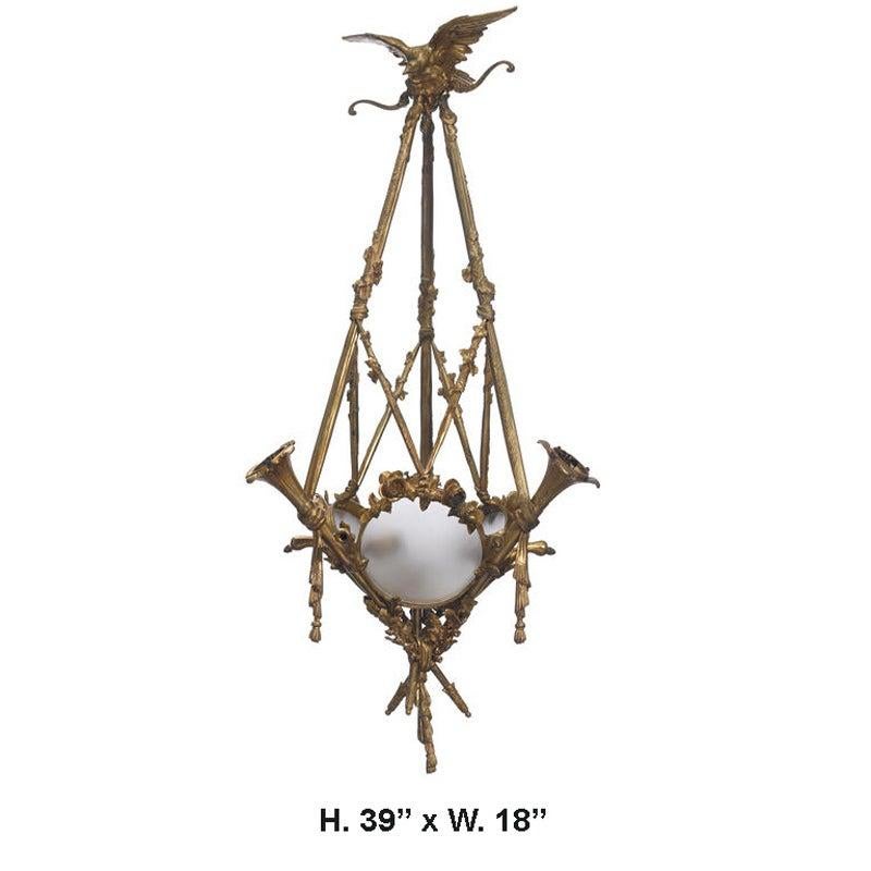 Unique French Empire style ormolu six light chandelier with eagle and trumpets.
19th century.

Gilt bronze eagle over three fine ormolu trumpets decorated in a floral and leaf motif encasing a frosted glass bowl terminating in ribbons.

  