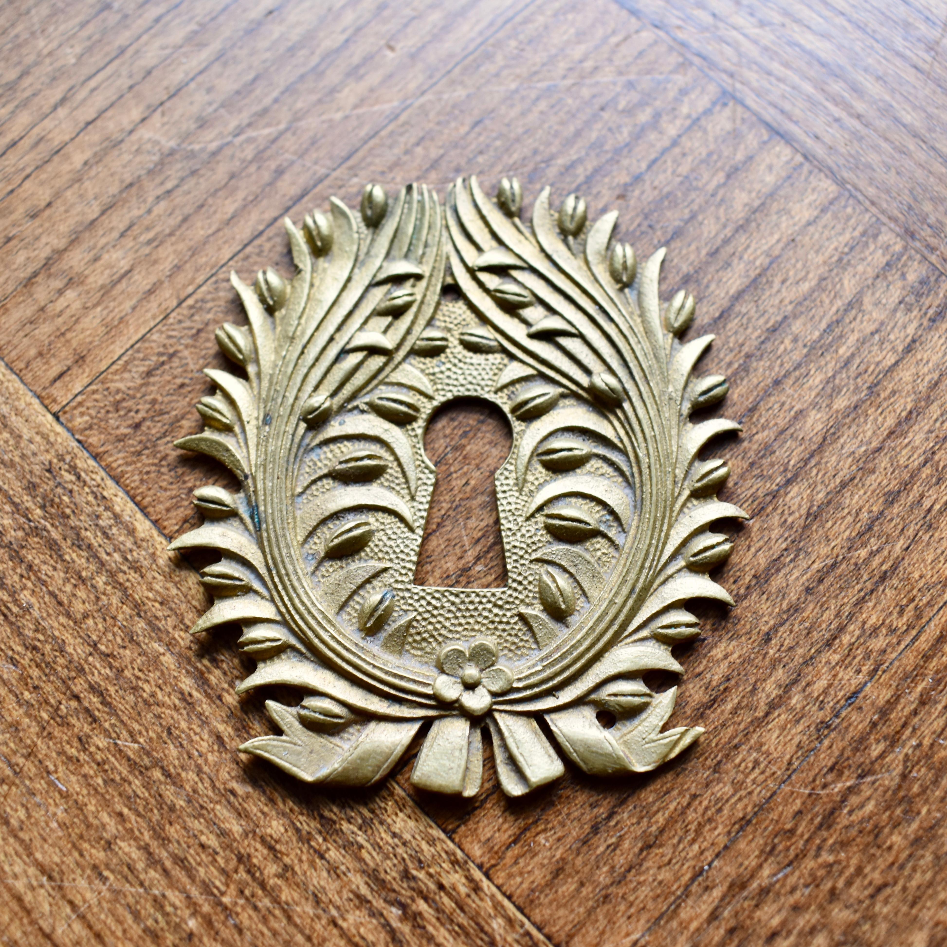 Add an elegant Parisian touch to your decor with this beautiful antique French ormolu, Beaux Arts escutcheon, circa 1900-1910. Designed to cover a keyhole on either a salon door, armoire or writing desk, showing an ornate relief design of a floral