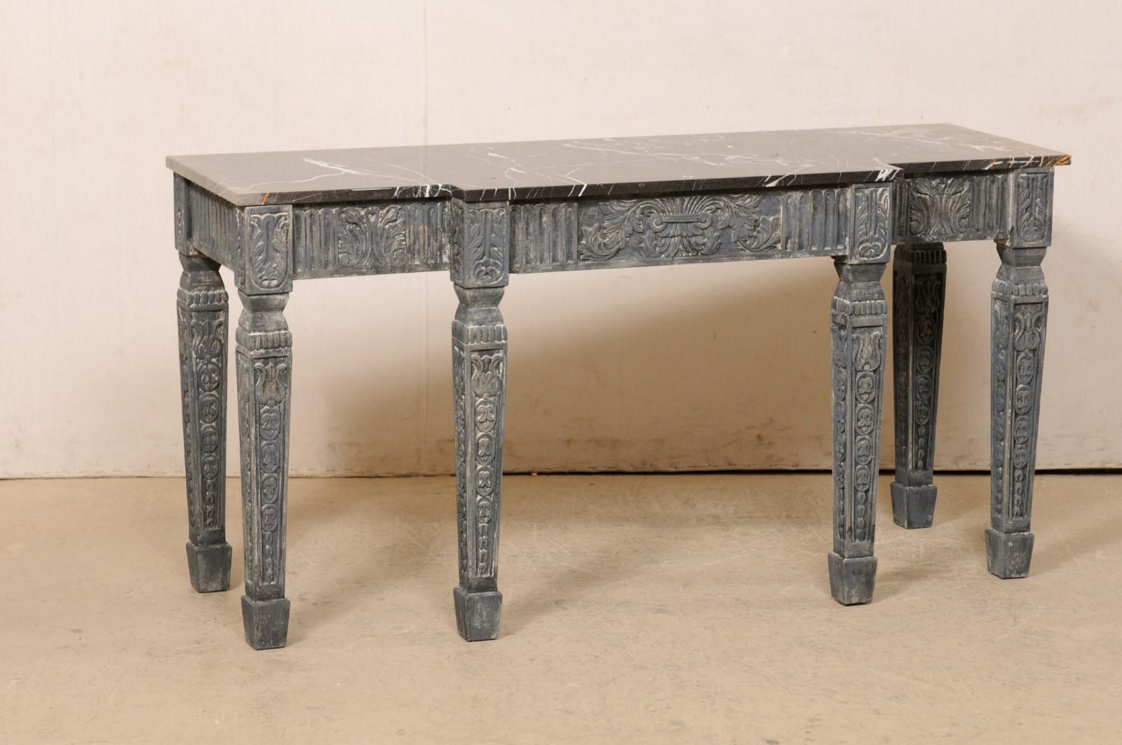 A French carved and painted wood console table with original marble top. This vintage table from France features a rectangular black marble top with white and rust veining (just shy of 5 feet in length), with a shallow break-front design at front