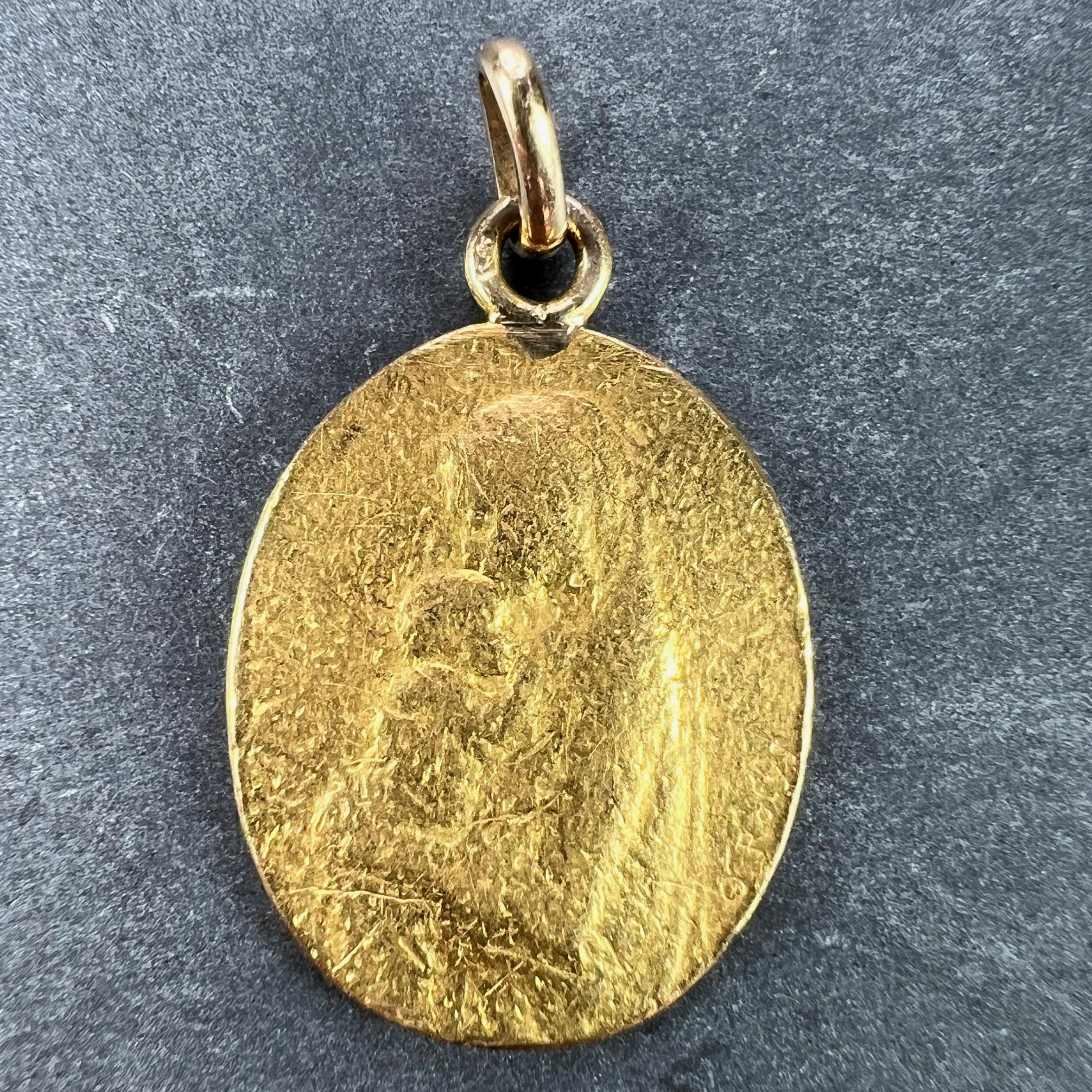 A French 22 karat (22K) yellow gold charm pendant designed as an oval disc with a carved relief of the Madonna and Child, signed O. Roty. The reverse depicting a branch of lilies with the Latin motto 'VIRGO SANCTA PUERUM CUSTODI' (Holy Virgin