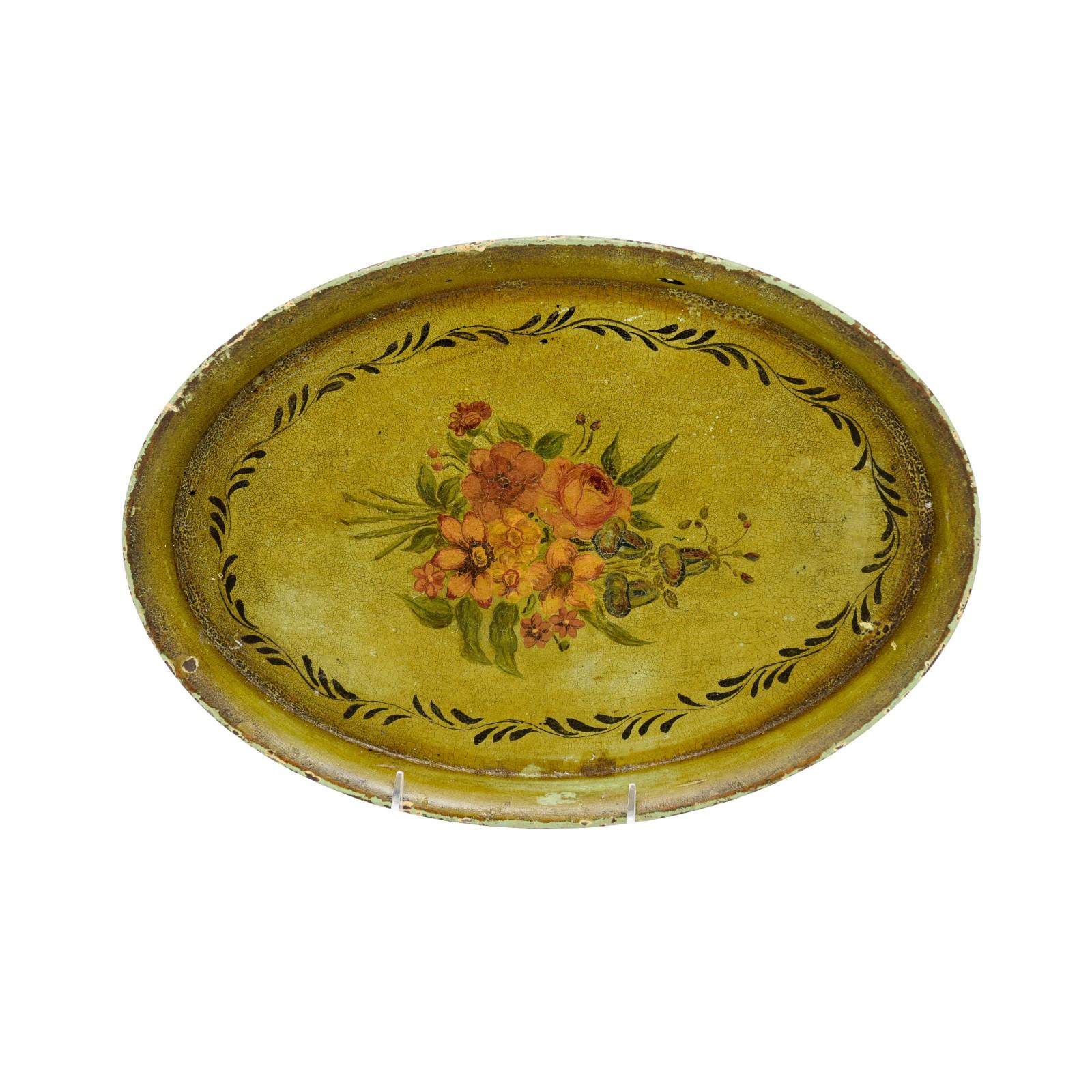 A French oval tole tray from the 19th century with hand-painted decor depicting a bouquet of roses, on olive green ground with rustic character. Created in France during the 19th century, this tole tray features an oval shape surrounded by a solid