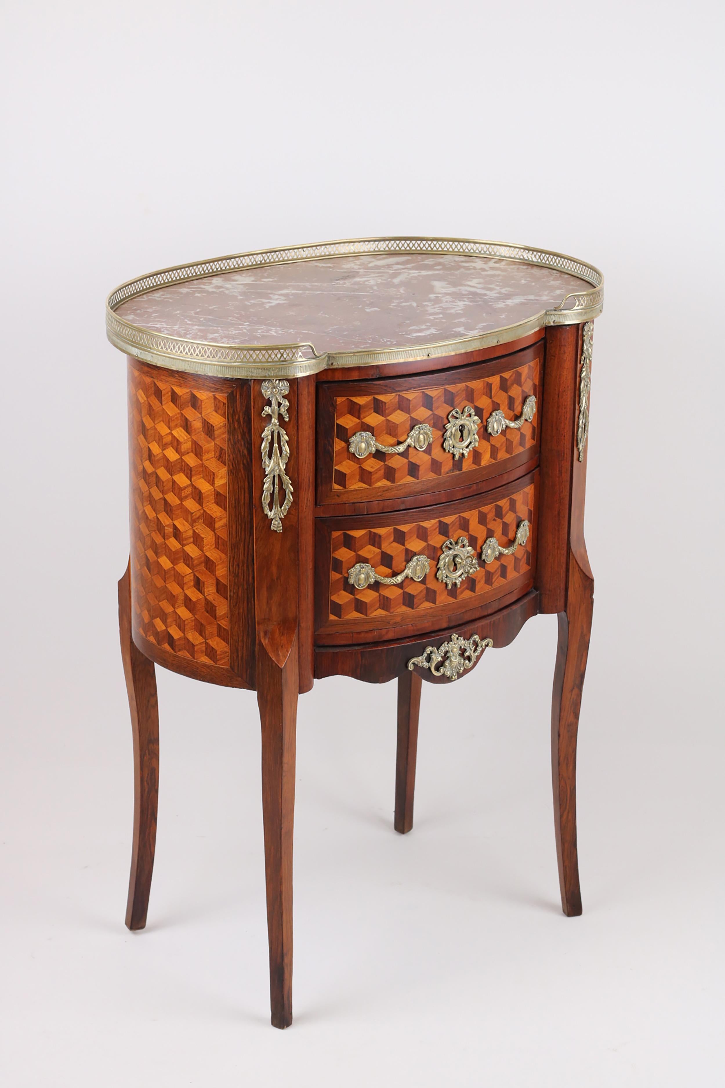 Cette élégante commode de forme ovale mêle harmonieusement des éléments des styles Louis XV et Louis XVI, mettant en valeur le savoir-faire raffiné de l'époque.

Avec ses deux tiroirs, sa marqueterie exquise, ses ferrures et ses frises en bronze