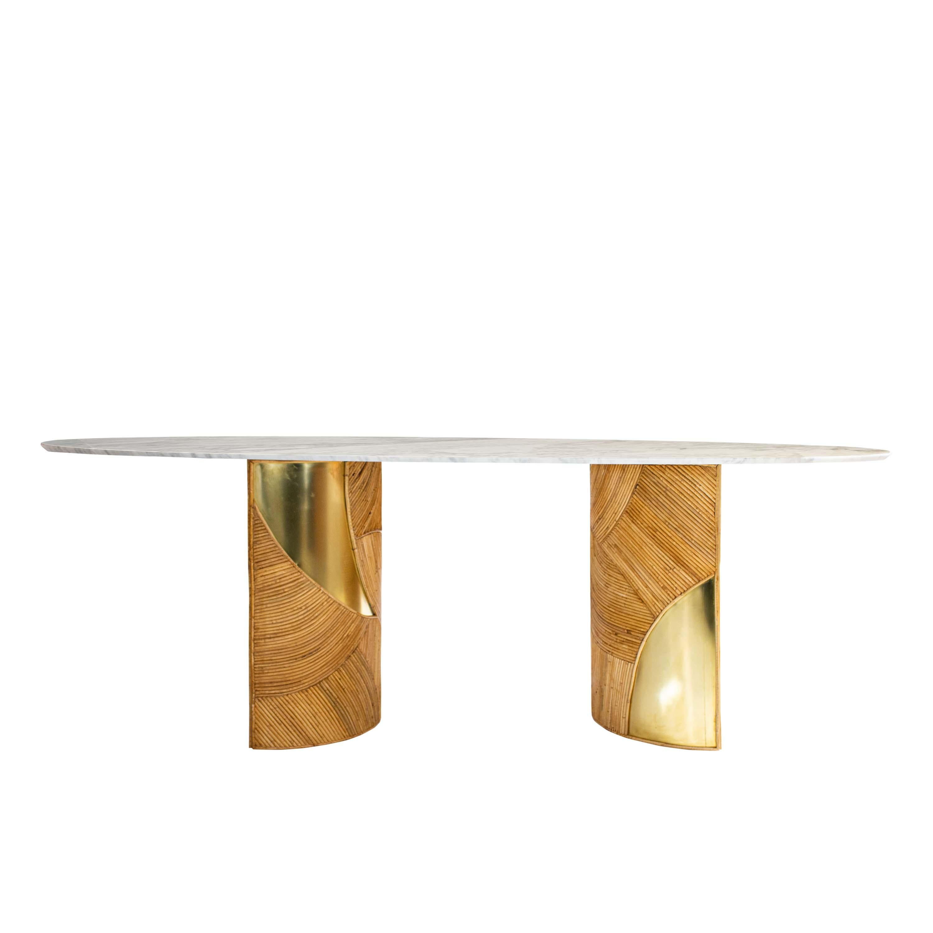 Elegante mesa de comedor francesa con tablero ovalado de mármol de Carrara que descansa sobre dos bases semicirculares artesanales de cañas de bambú con detalles de latón. La encimera de mármol presenta un borde estriado con un acabado pulido, que