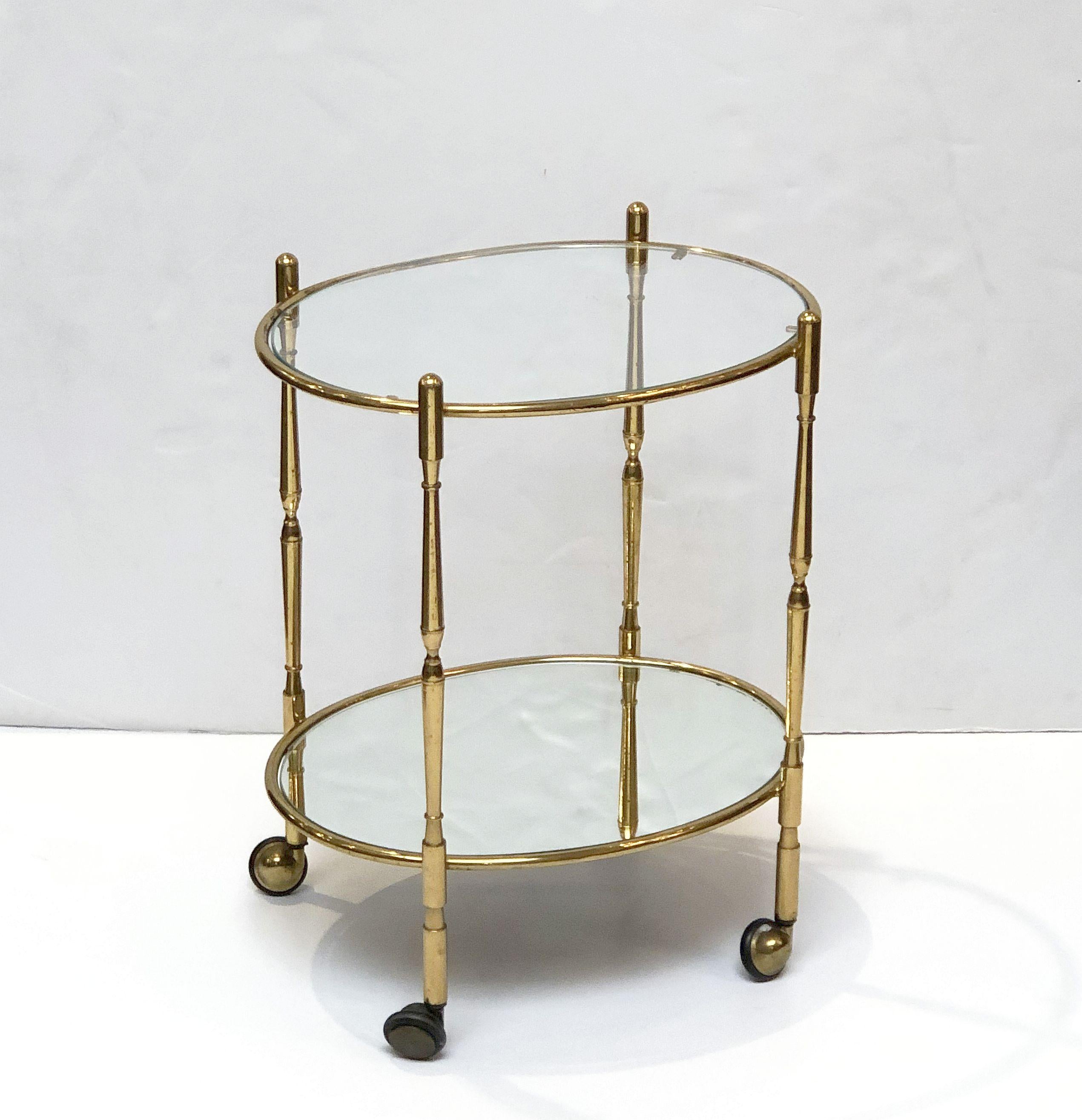 A vintage French oval bar cart table or drinks cart (serving trolley) in brass, with a top tier of glass and a bottom tier of mirrored glass, on rolling caster wheels. 

Perfect for use as a side or end table.