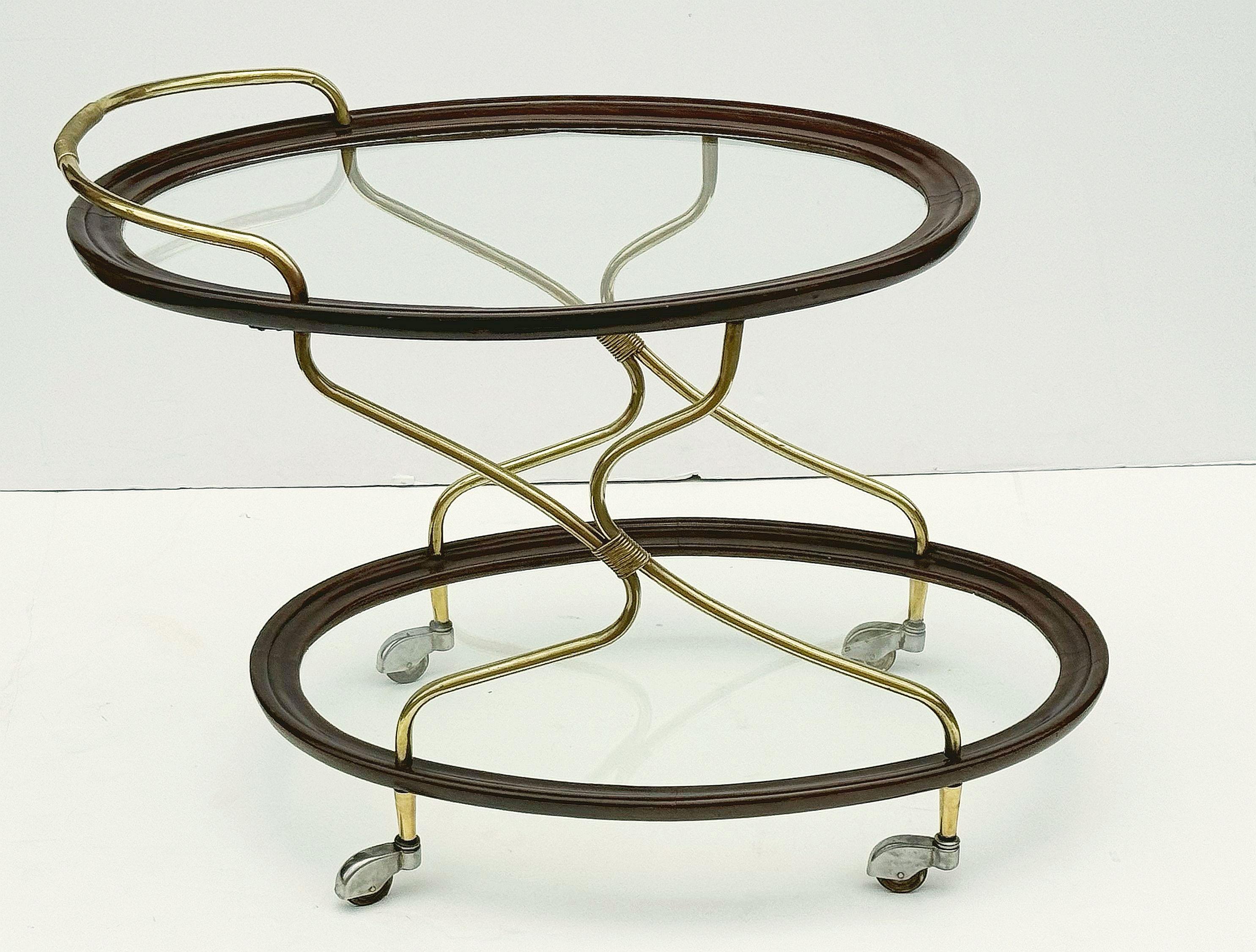 Carrello ovale francese d'epoca in mogano e ottone, con due piani ovali in vetro, ciascuno con telaio in mogano modellato, con eleganti supporti in ottone a serpentina e ruote piroettanti.

Perfetto per essere utilizzato come tavolino o