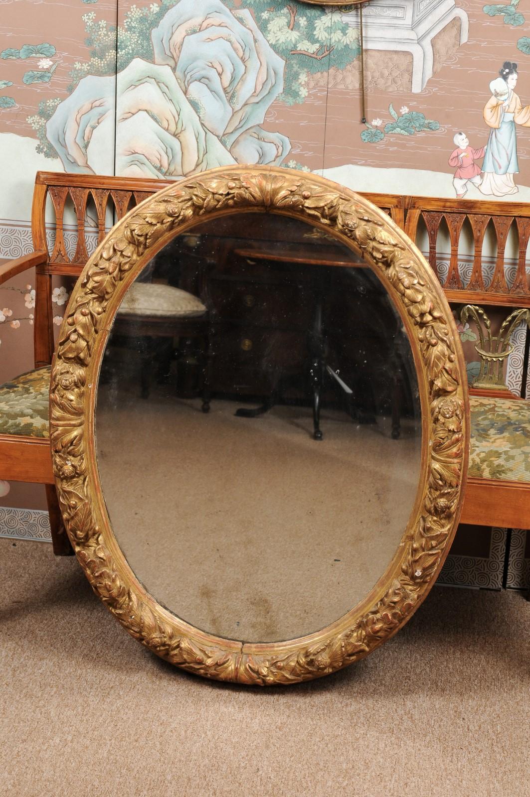 A French oval giltwood mirror with foliage carving. The mirror plate with some age.