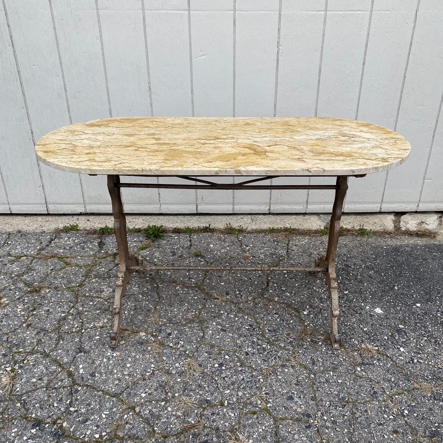 Versatile French marble top oval cafe table or writing desk with a classic Provincial iron base. Marble is a stunning beige marble with veining. Very nice edge on all four sides - and could be in the center of a room, and could also serve as a