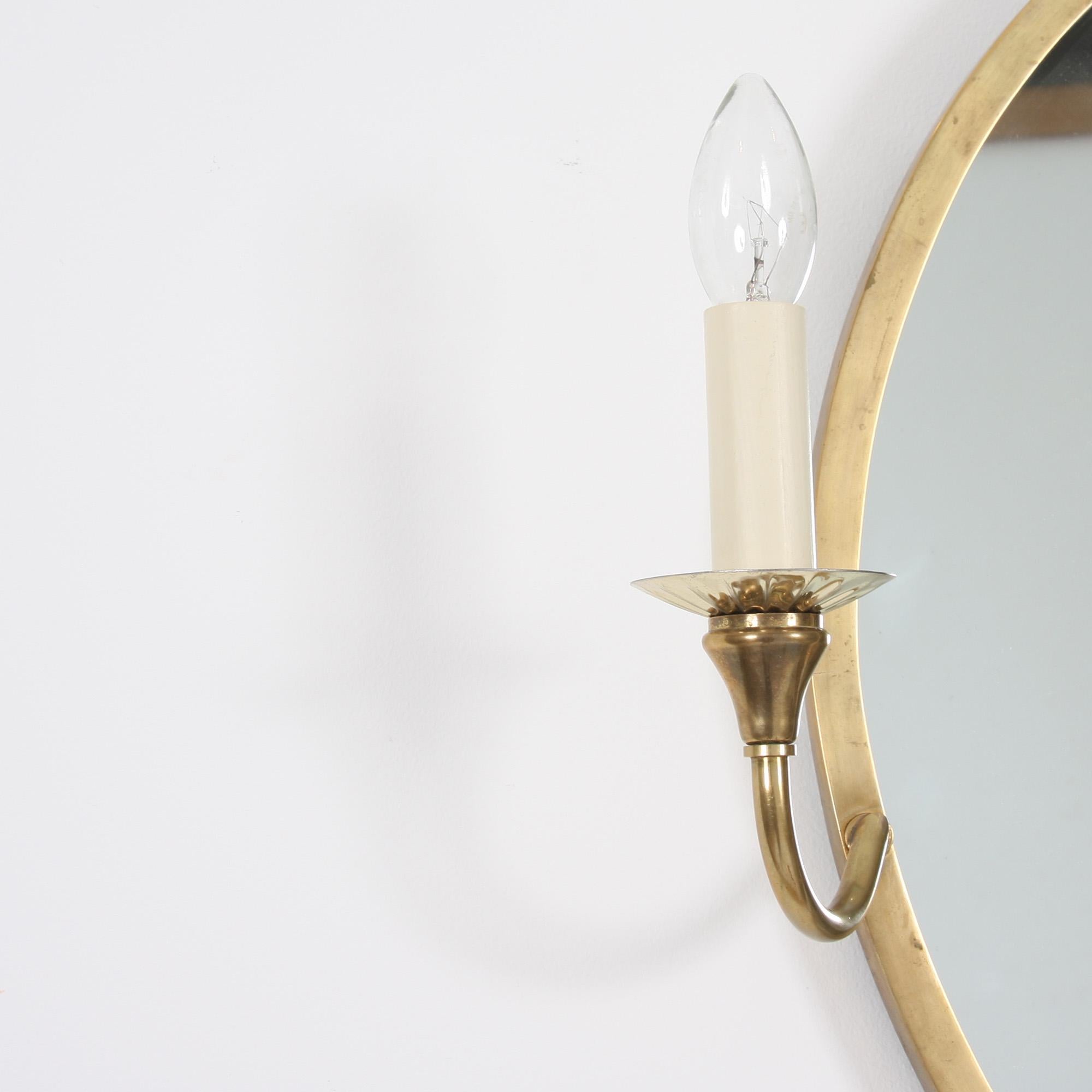 This beautiful brass oval-shaped mirror with rewired candle lights originates from 1960s, France.