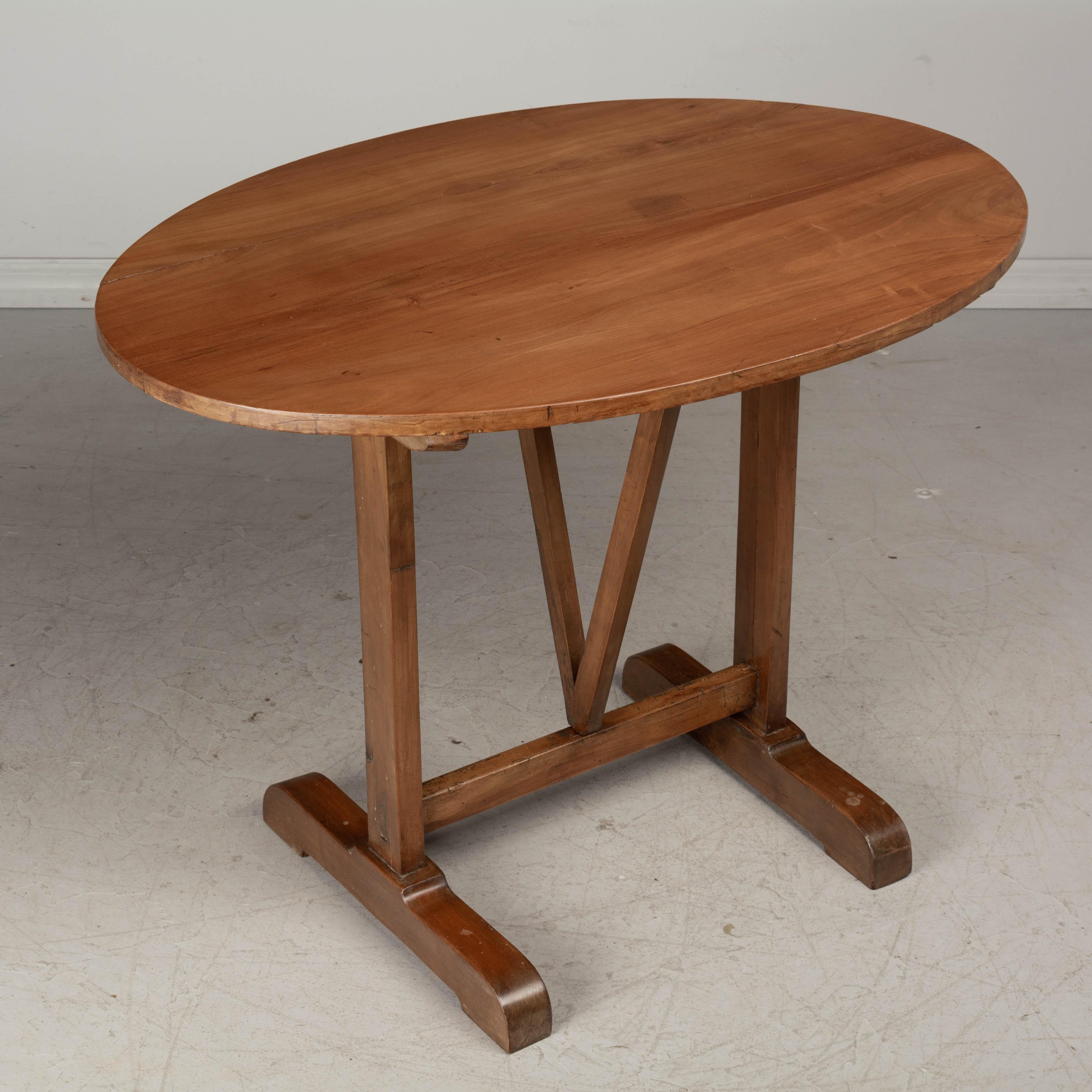 A French oval tilt-top side table made of solid cherry wood. Waxed patina. 
Overall dimensions when opened flat 39