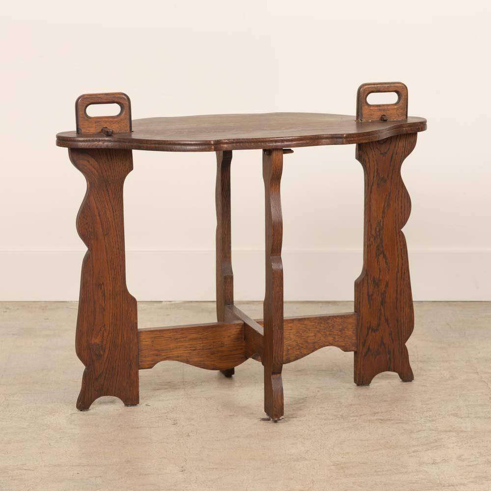 Wonderful oak wood side table from France, 1940's. Ornate oval top with handles and carved detail on legs. Perfect for a side or drink table. Original finish shows nice age and patina. 