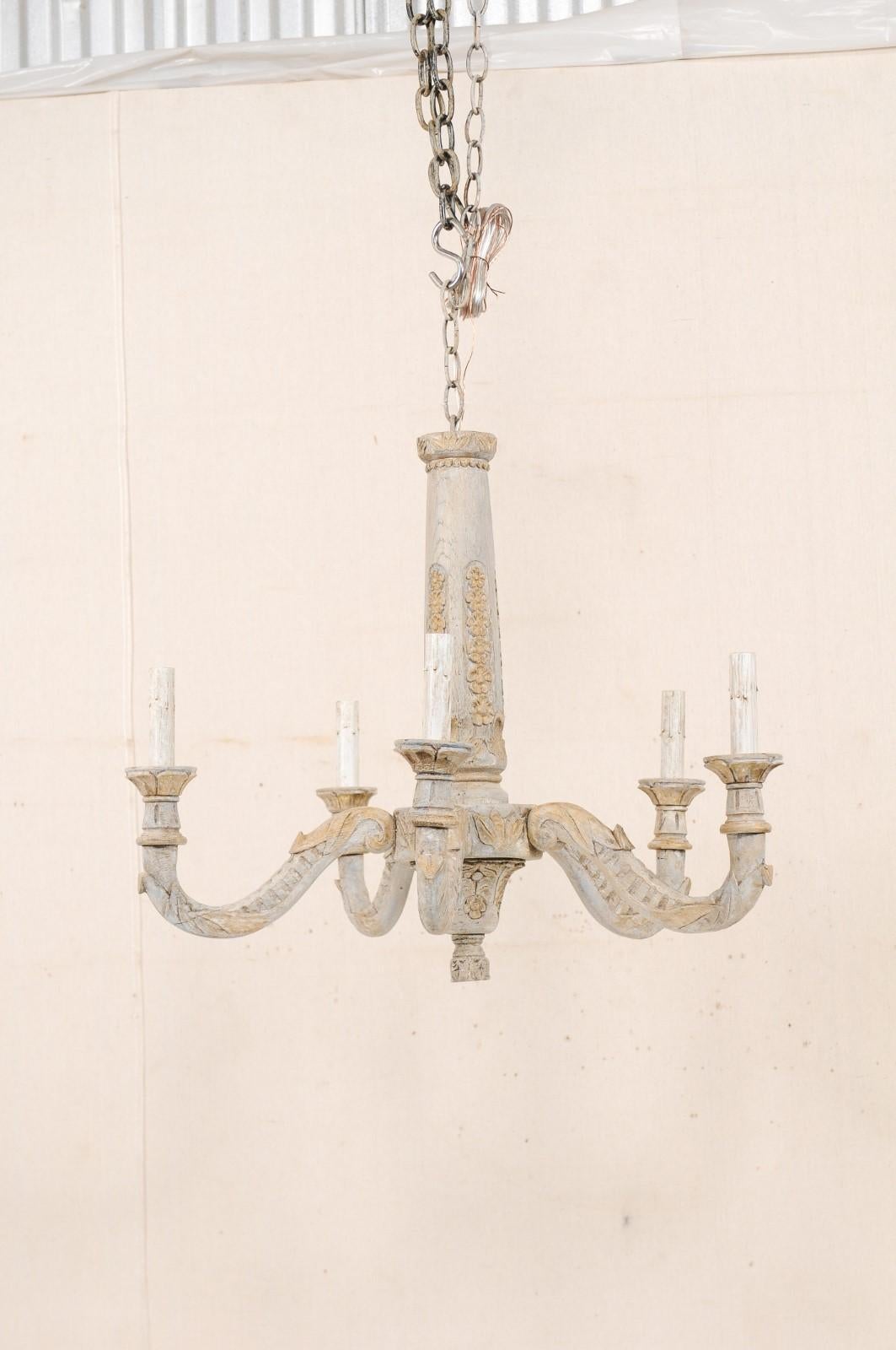 A French five-light carved-wood chandelier from the mid-20th century. This vintage chandelier from France has a central column, nicely carved with petite flower heads set vertically about it's perimeter, acanthus leaf motifs about it's central
