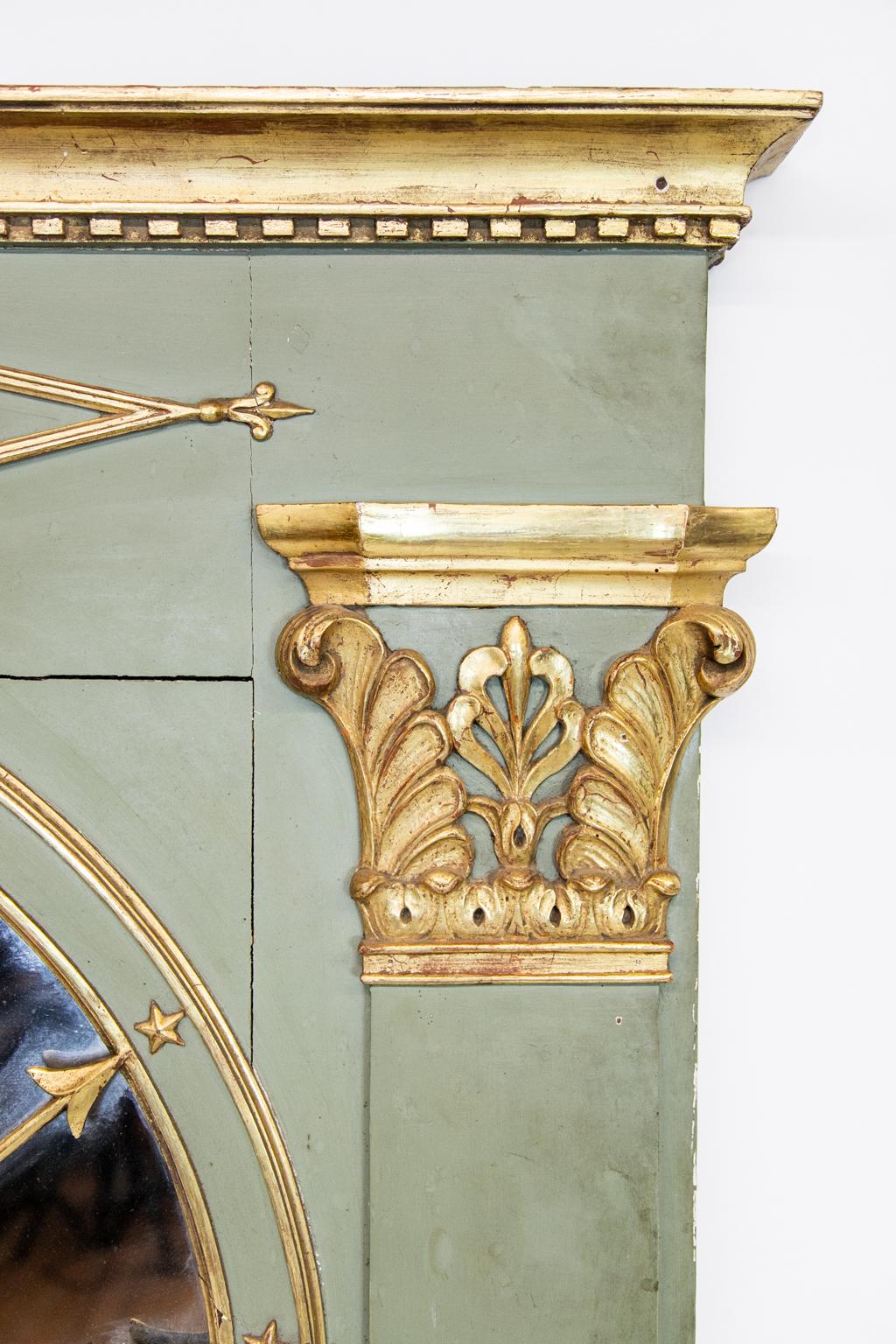 French painted and gilt mirror has simulated pilasters on the sides with carved elongated marquees with carved center medallions. It is tipped at the ends with fleur-de-lis. It has gilt Corinthian capitals and an arch mirror depicting seven arrows