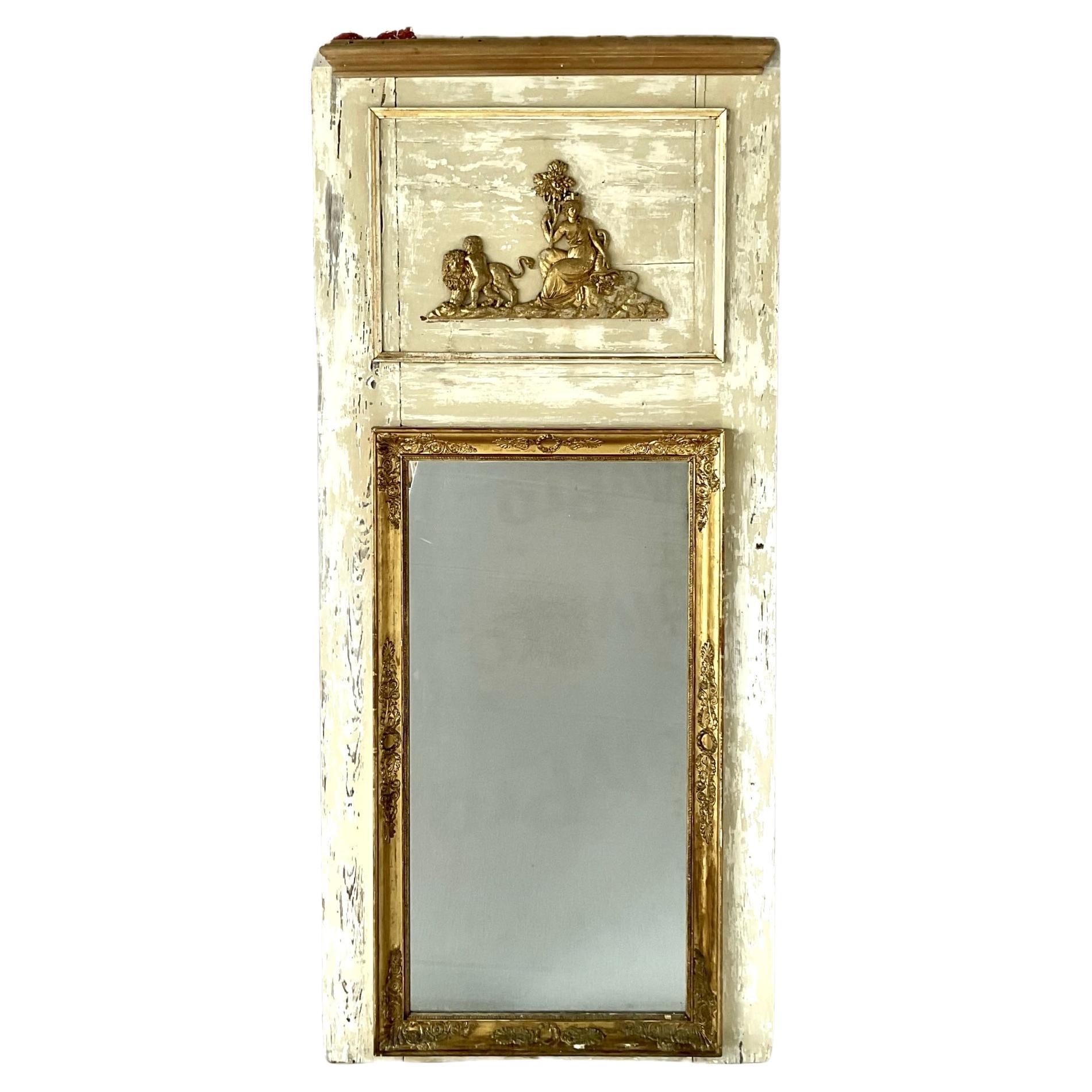 Espejo Trumeau de principios del siglo XIX, francés, pintado y dorado a mano.  El espejo presenta un panel narrativo decorativo dorado sobre la placa del espejo que muestra a una mujer serena junto a un niño pequeño y un león, todo ello en un