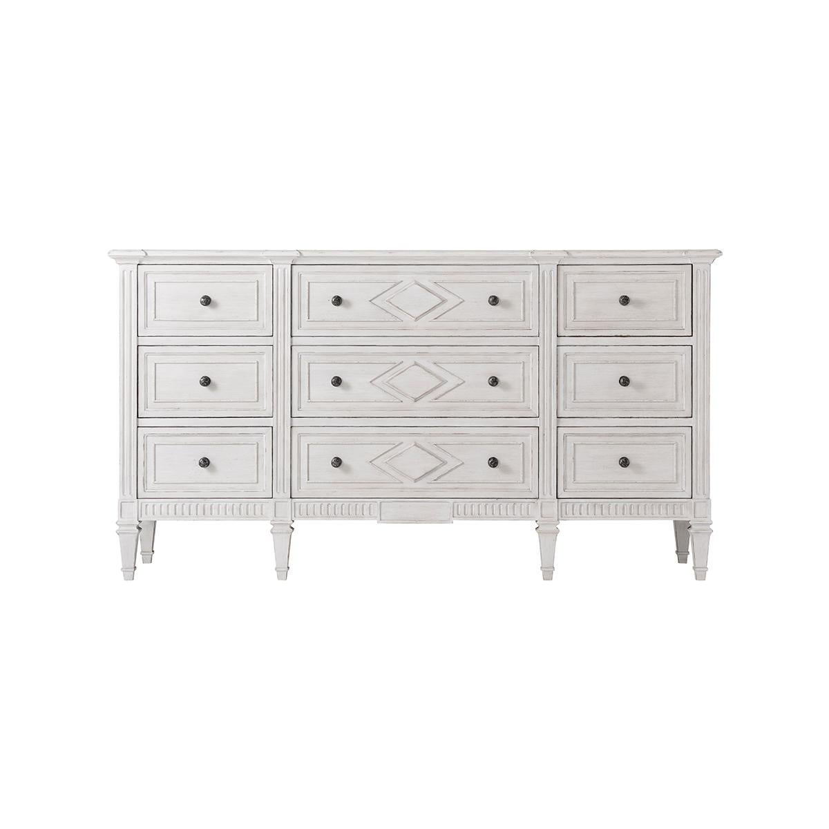 In a painted antique finish with a molded edge rectangular top, nine paneled drawers with lozenge detailing motifs, antiqued pewter handles, with a fluted base and raised on square tapered legs. In the French Directoire style.

Dimensions: 70