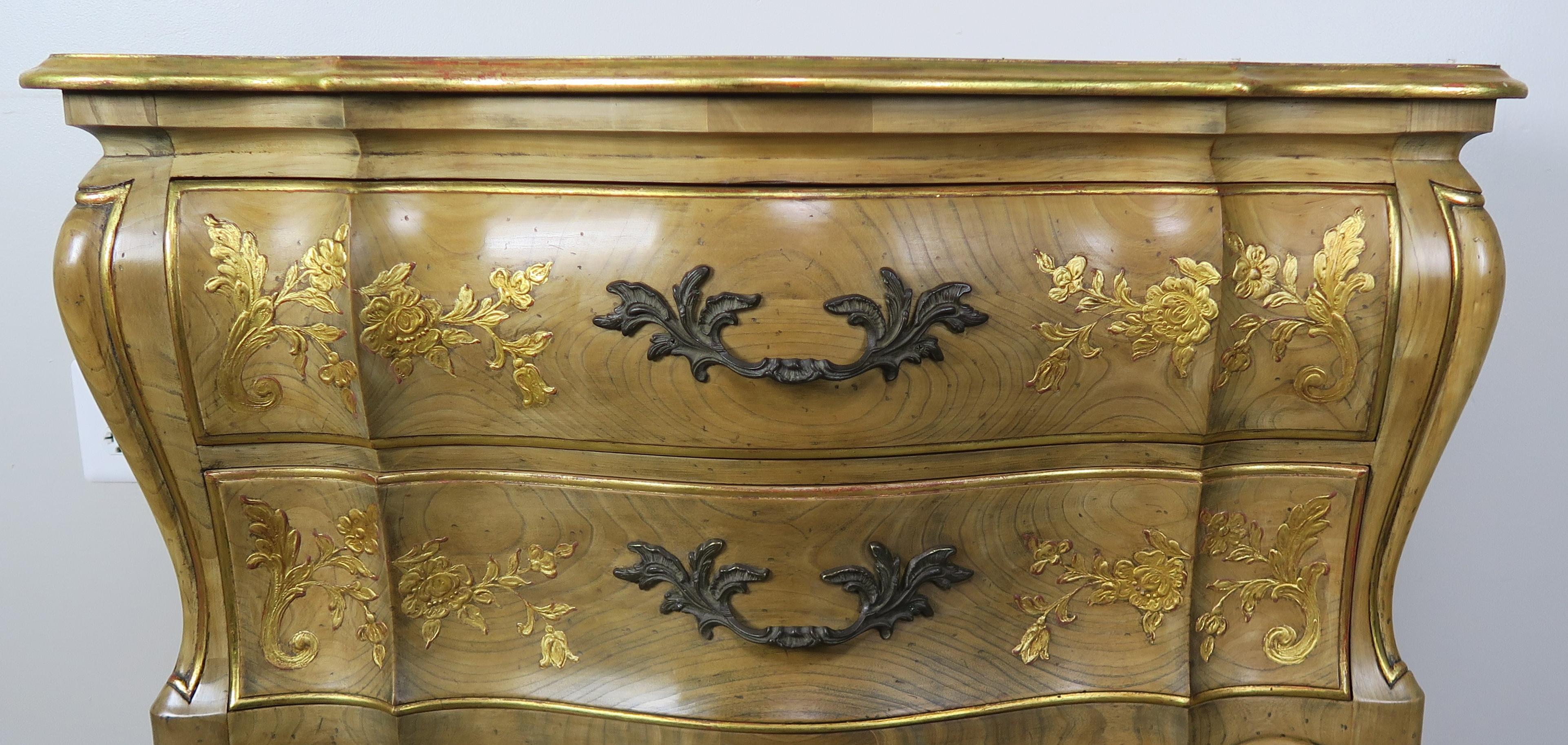 French two-drawer chest beautiful painted in a metallic gold chinoiserie depicting flowers throughout. The two drawer chest stands on four cabriole legs with a simple pad foot. The piece is made from elm and has beautiful raised chinoiserie painting