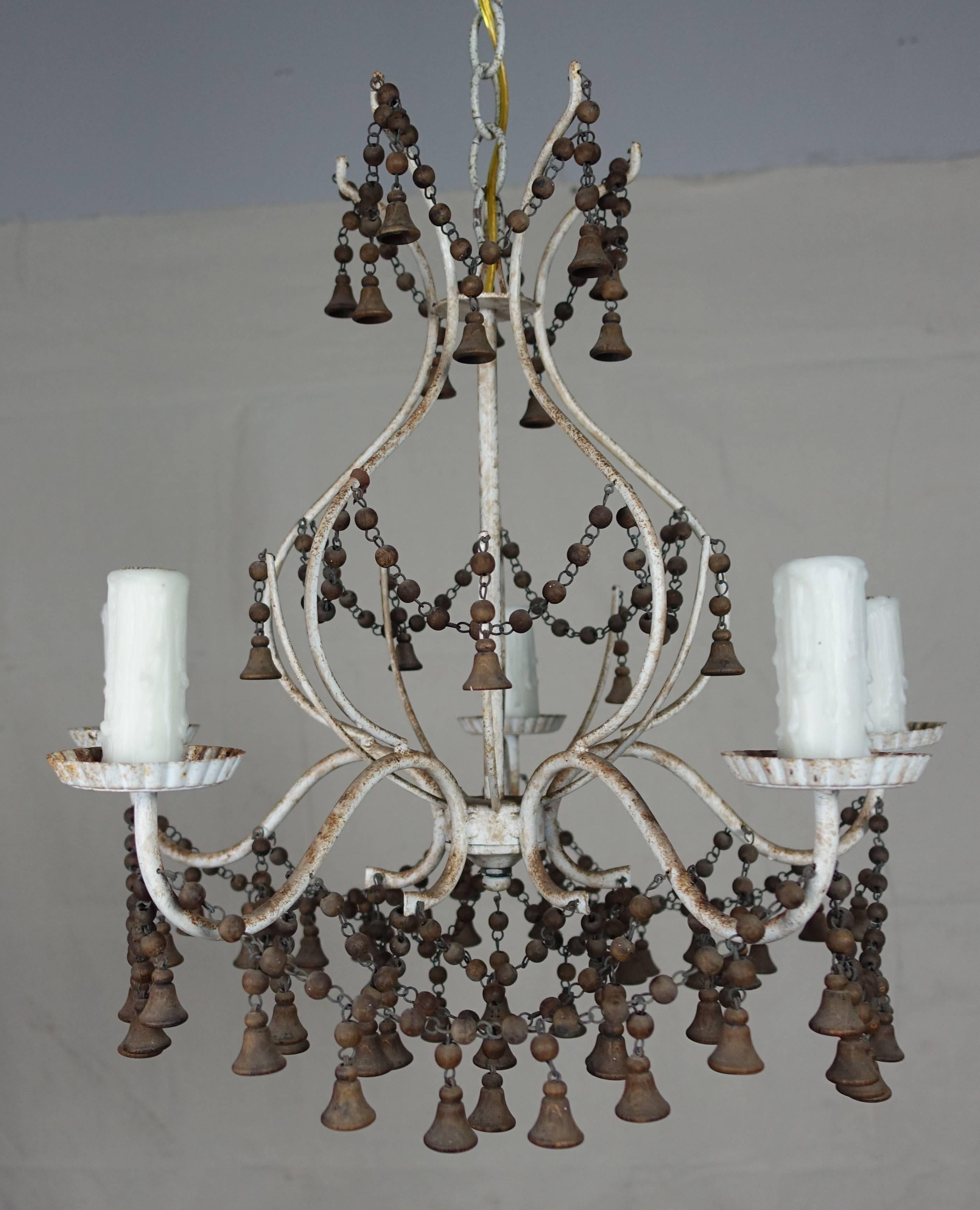 1920s French white painted metal framed five-light chandelier adorned with garlands of natural colored wood beads and bell shaped tassels throughout. The chandelier has been newly rewired with drip wax candle covers and includes chain and canopy.