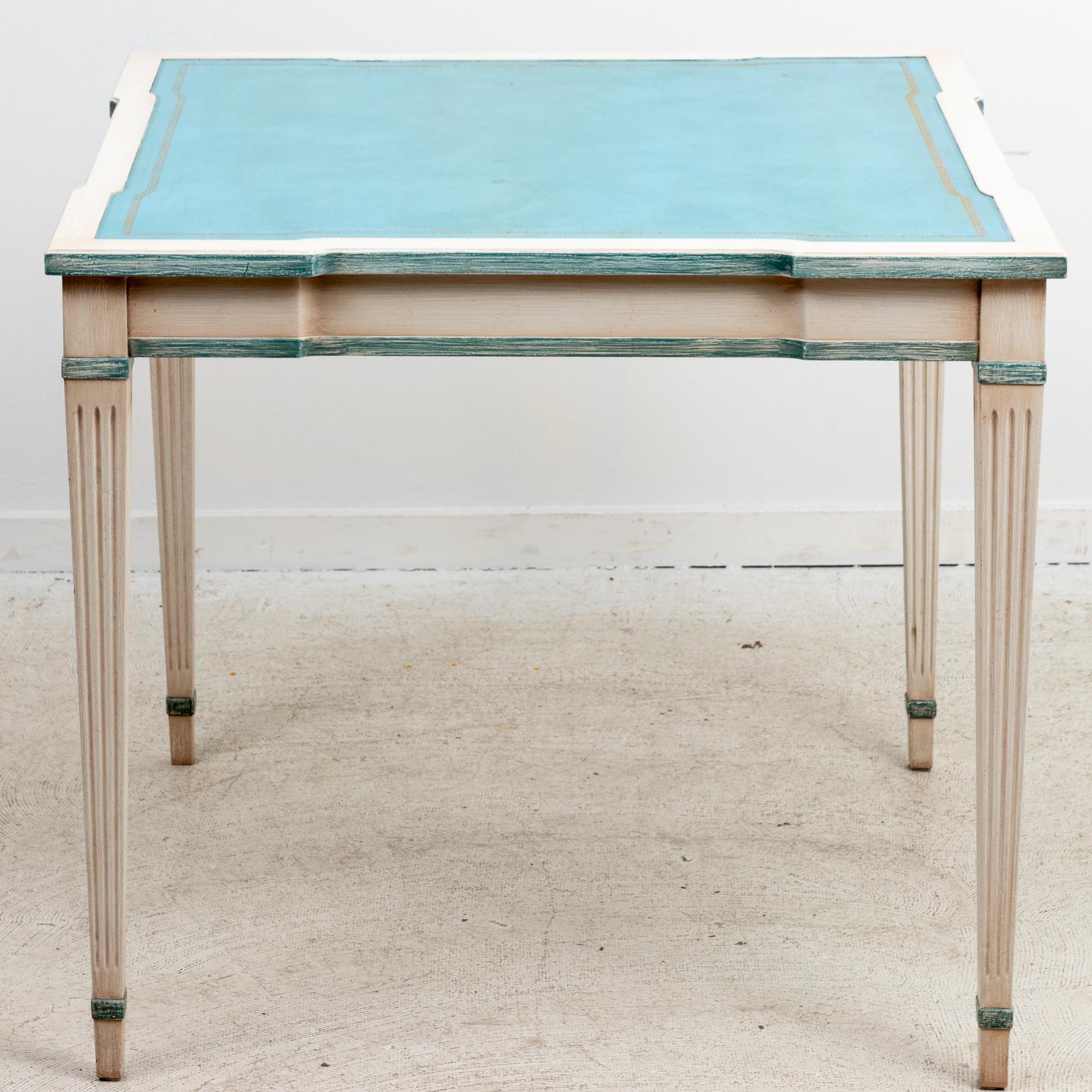 Circa 1940s French painted Louis XVI style white game table with aqua blue tooled leather top and fluted, tapered legs with aqua blue color accents over off white patina. Made in France. Please note of wear consistent with age including slight