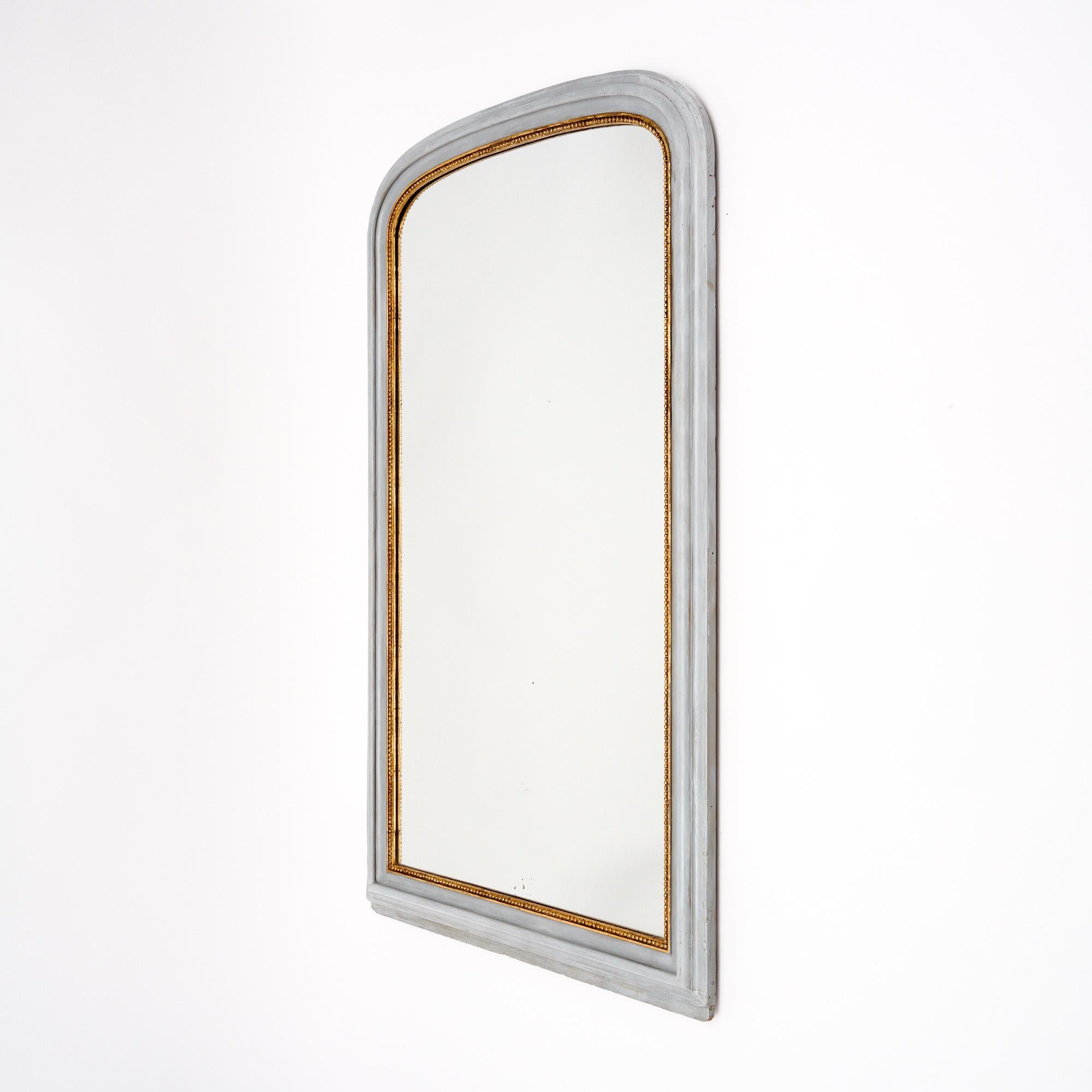 Grand Mirror from the Louis Philippe period from France. This piece has a hand carved wood frame with the classic curved upper corners of the mirror. The mirror is painted a dove gray with a gold leaf trim. The mirror is the original mercury mirror.