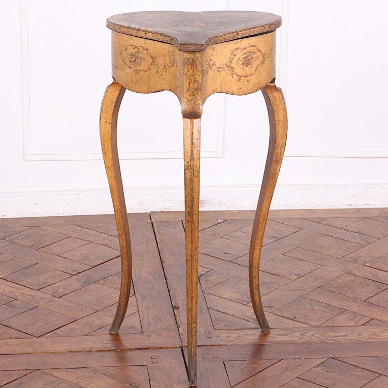 An unusual French heart-shaped sewing table with painted floral details to the sides and a painted scene of figures in a woodland setting on the top (showing considerable wear). A pretty French 'shabby chic' piece on elegant long serpentine legs.
 