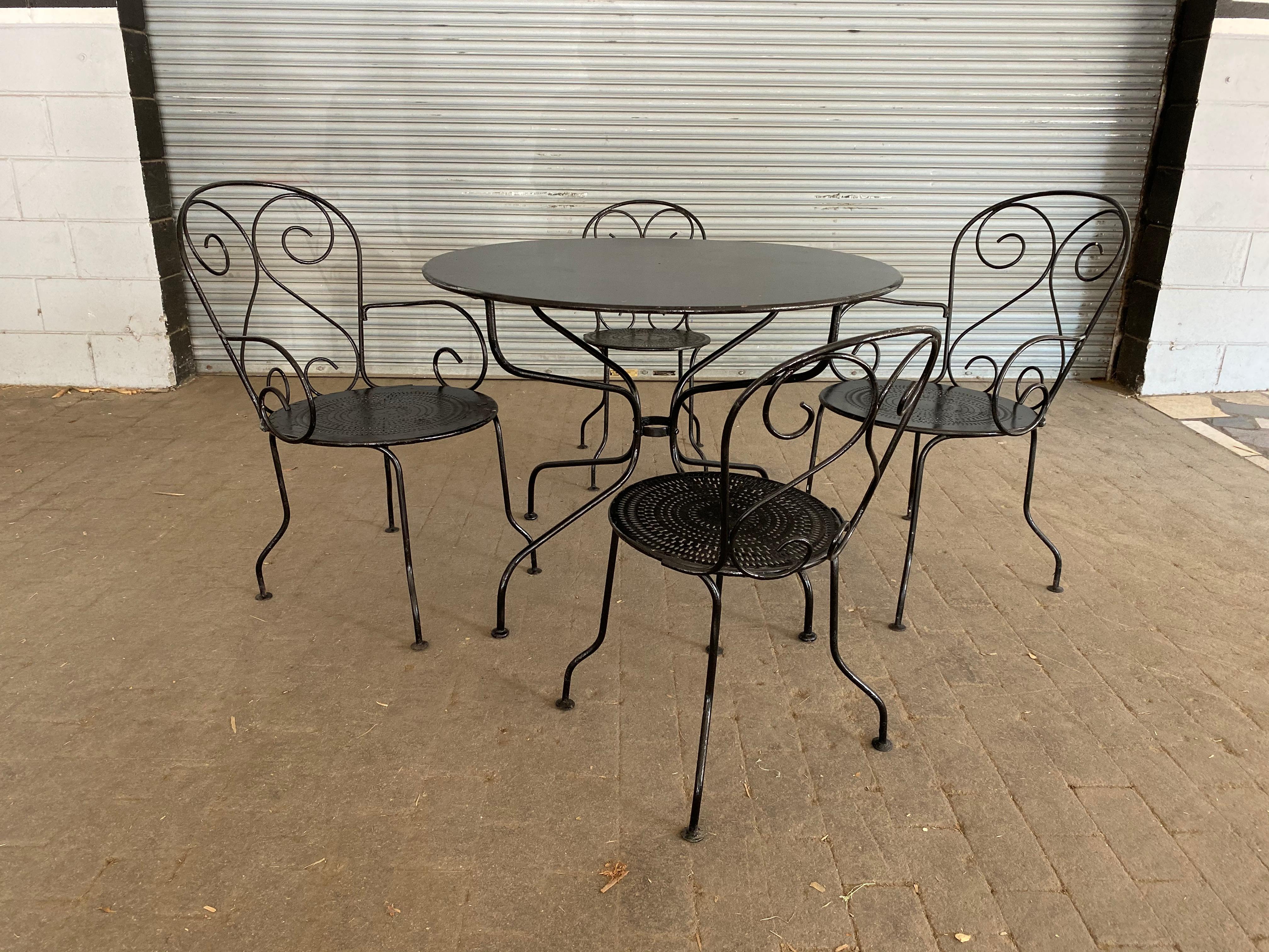 5 piece French black painted garden set consisting of a 38 ½” diameter table and 2 side chairs and 2 armchairs. The early 20th century iron table has a new top. The 4 chairs are more recent, made in France in the 1990s. The entire set has been