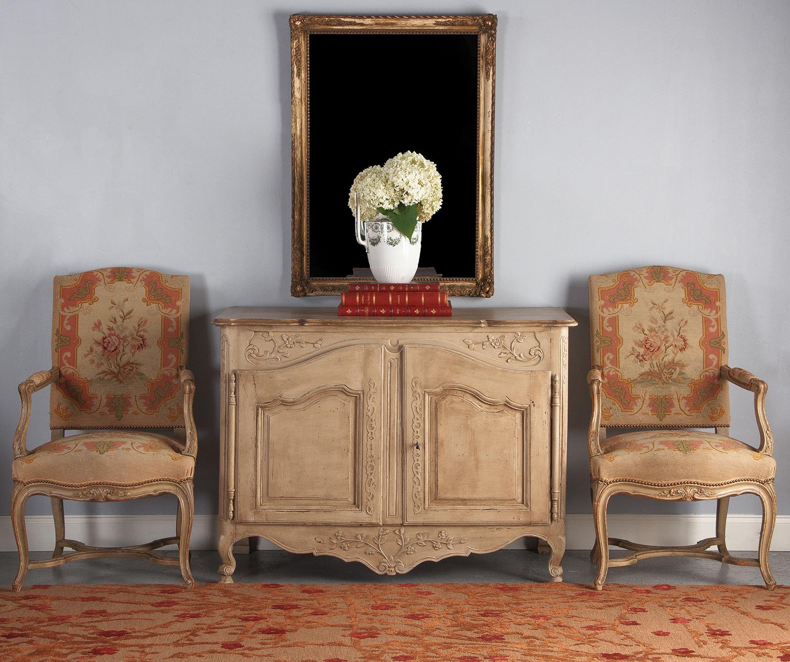 A decorated 19th century Provencal painted Louis XV style buffet. Constructed of pine, the piece is painted in a distressed muslin tone and stained dark brown on the interior. Molded and scalloped top, paneled sides and paneled, arched double doors