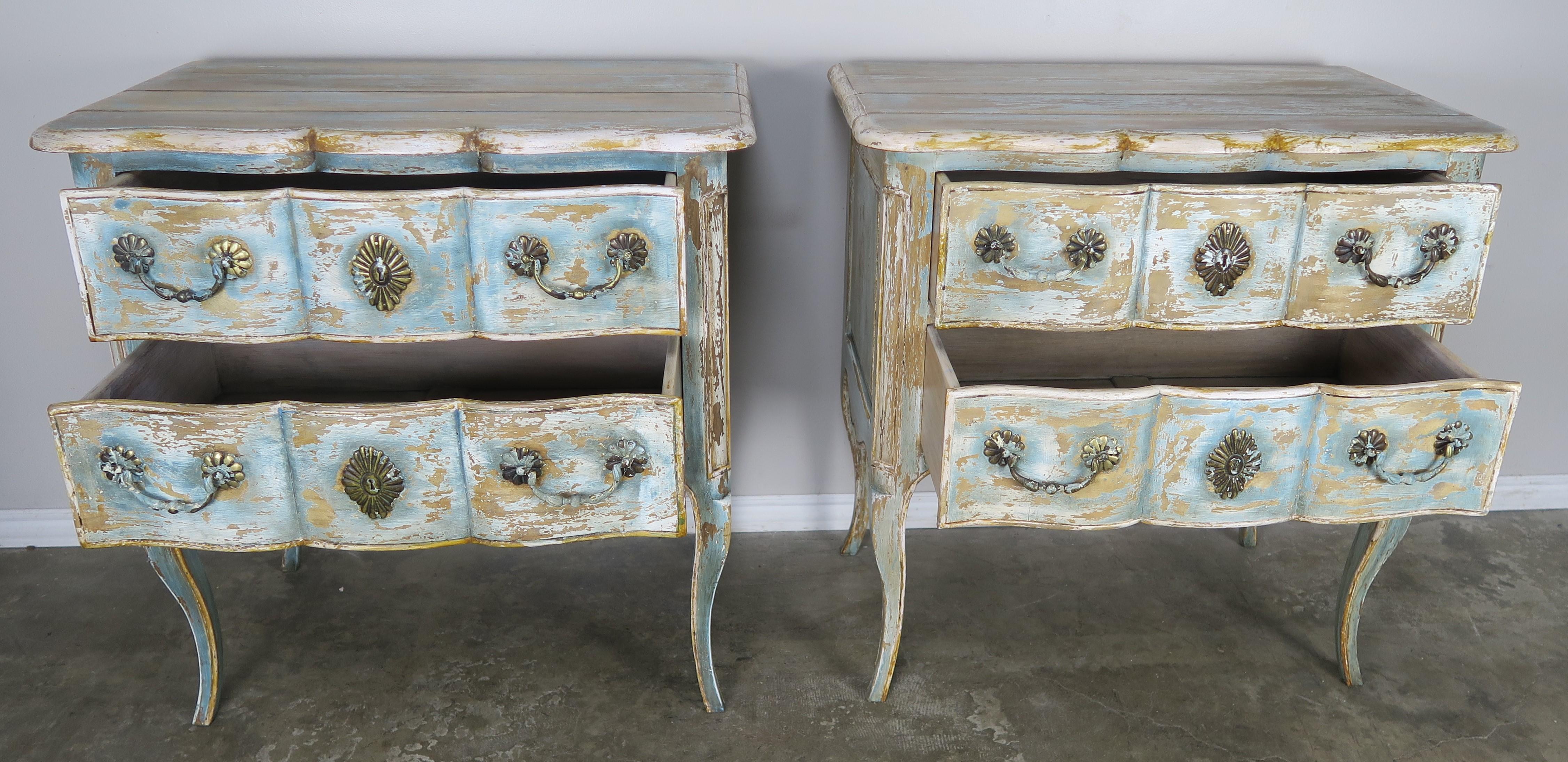Pair of French painted Louis XV style two drawer commodes that would make perfect night tables, standing on cabriole legs with rams head feet. Beautiful distressed and worn painted finish throughout. Original brass handware.