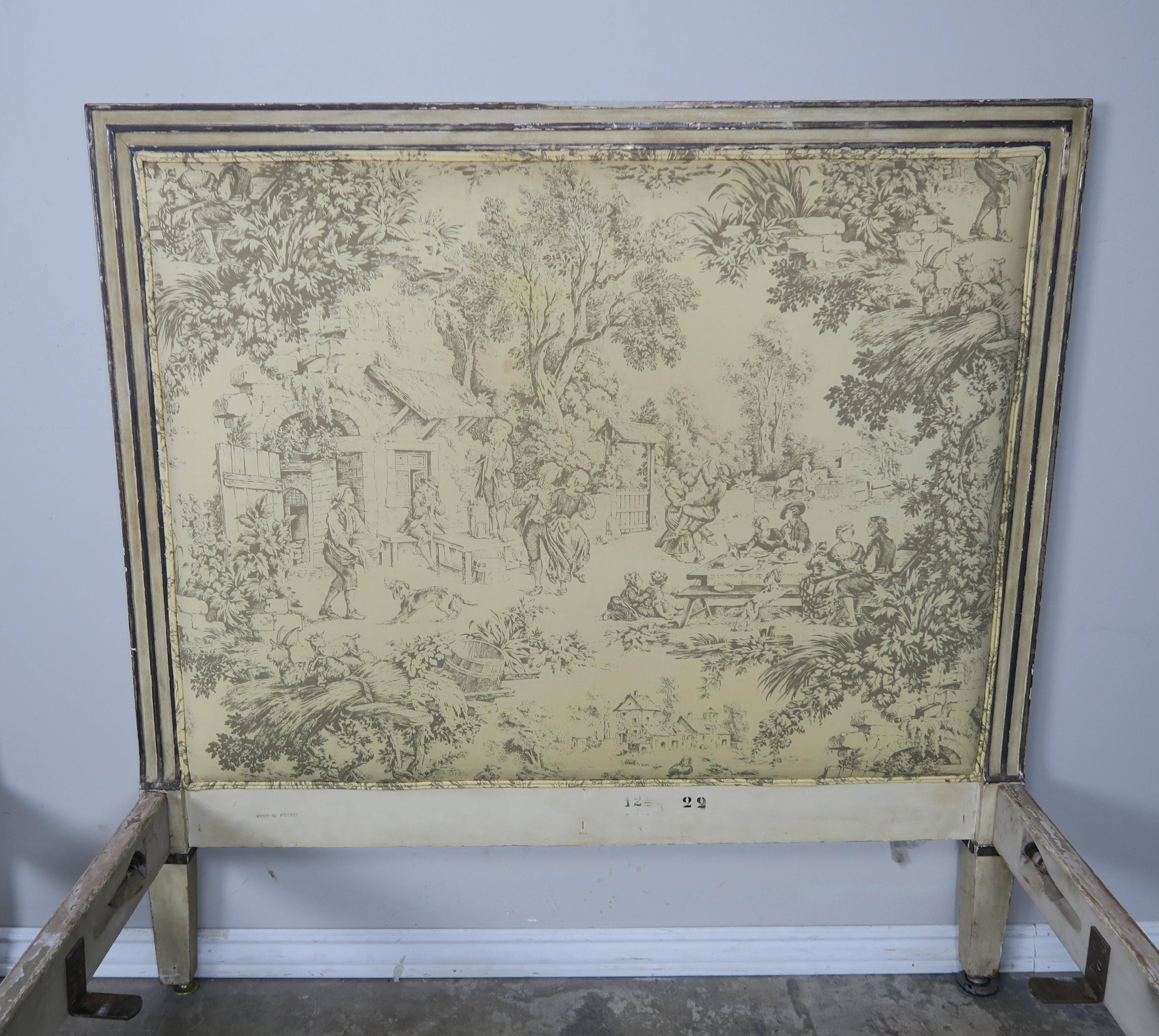 Pair of French painted Louis XVI style bed frames upholstered in vintage printed toile fabric with double self cord detailing. The beds include headboards, footboards, and side rails. Stamped 