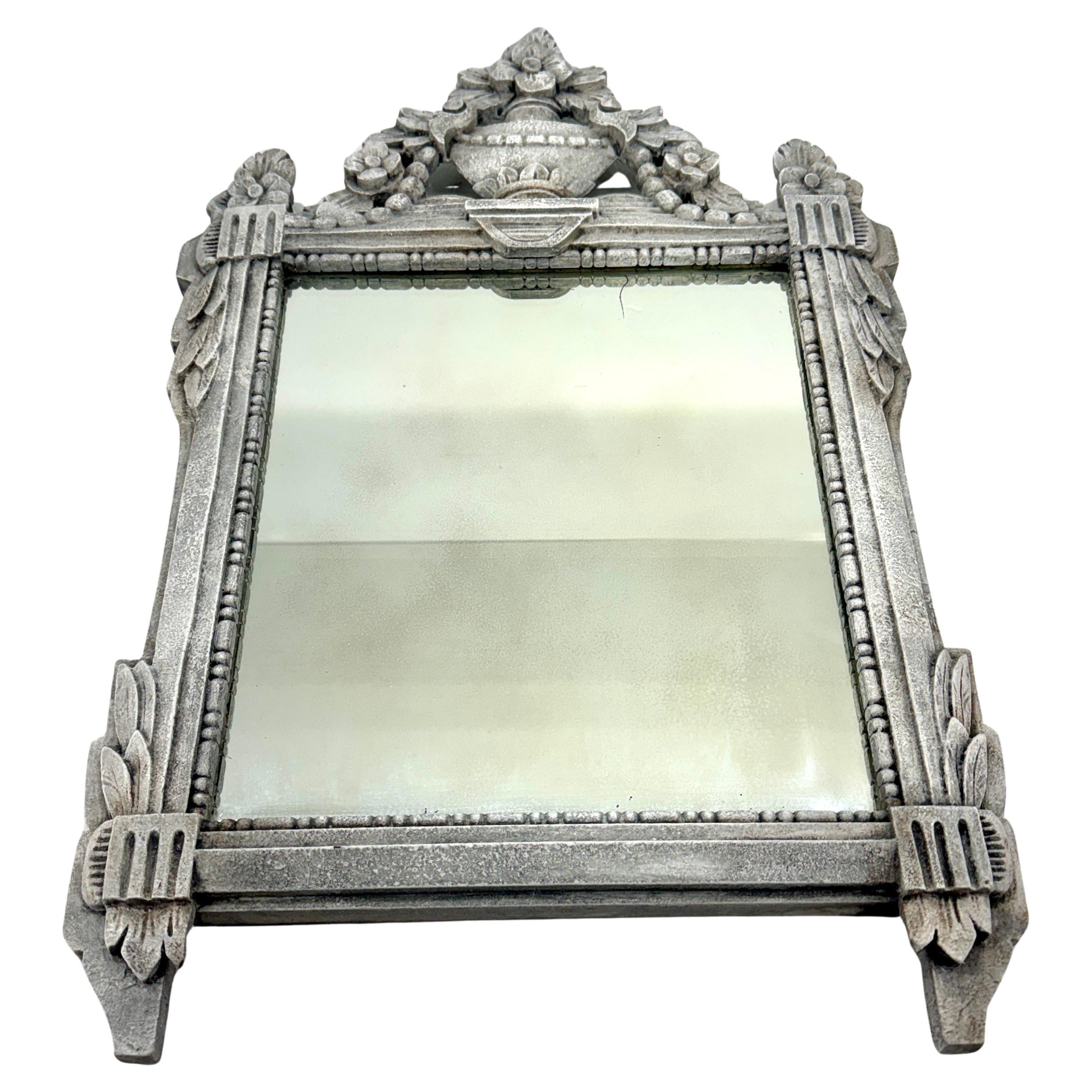 Specchio dipinto in stile Luigi XVI intagliato a mano proveniente dalla Francia. Questo specchio presenta un'elaborata urna o vaso sulla parte superiore con fiori all'interno e intorno. È sicuramente un pezzo versatile che può essere utilizzato in