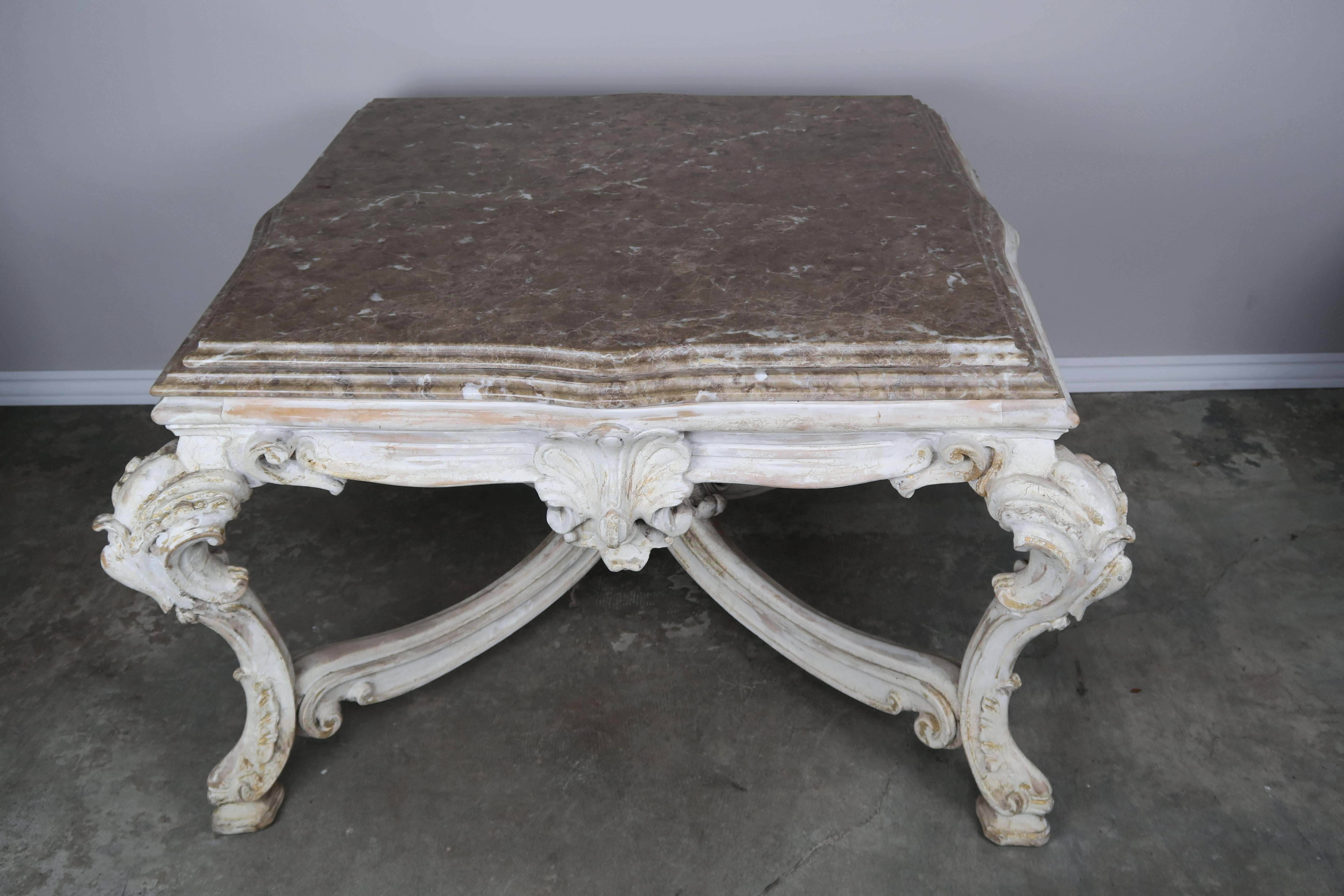 French carved Louis XV style wood painted coffee table with soft colored brown marble top. Ornate cartouche carved cabriole legs connected by a bottom stretcher that meets at a shell finial.