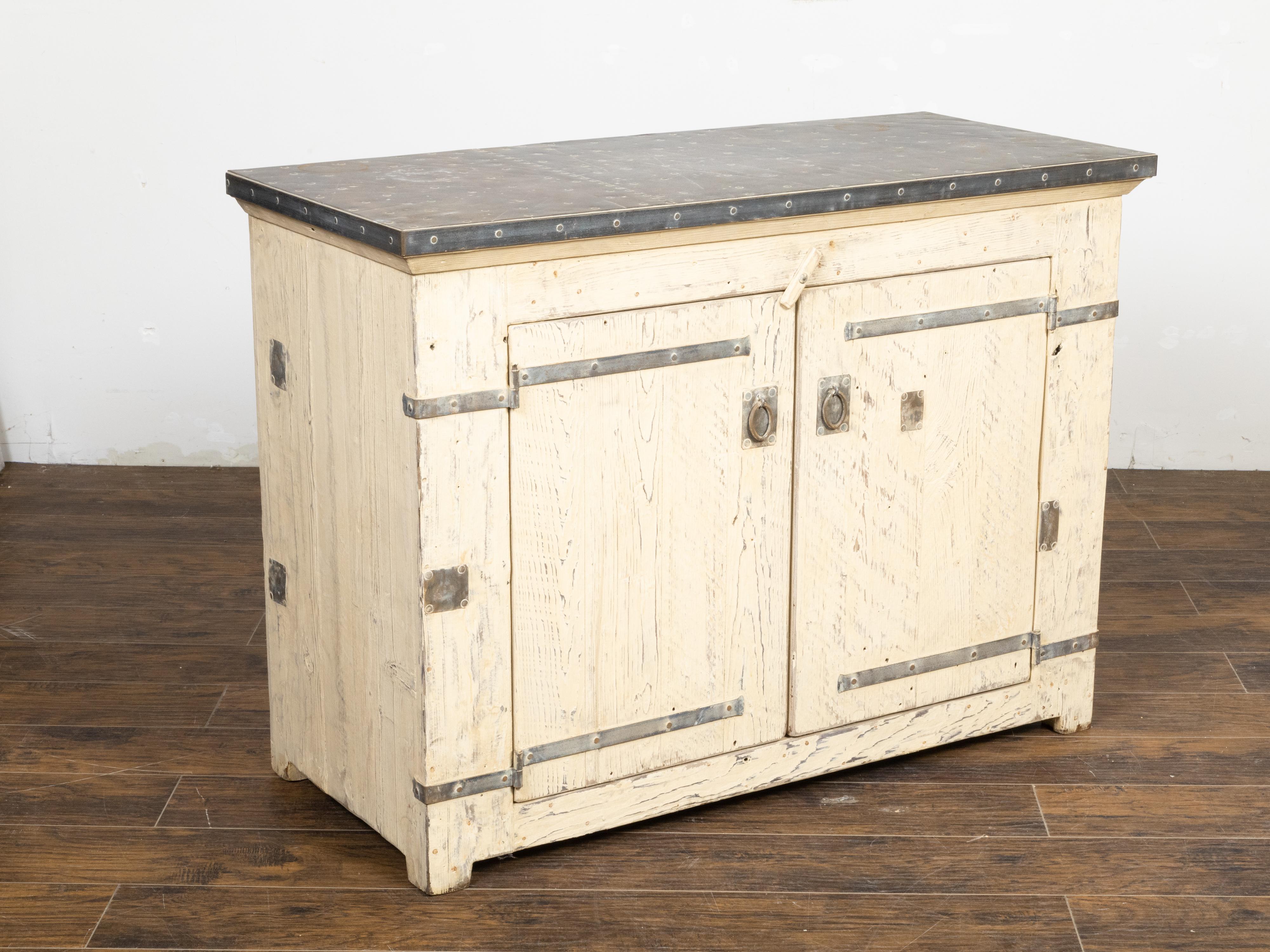 A painted pine buffet from 21 st c., with zinc top, two doors, light color, metal accents and rustic character. The painted pine buffet charms us with its simple lines as well as its rustic and industrial look. The piece features a rectangular zinc