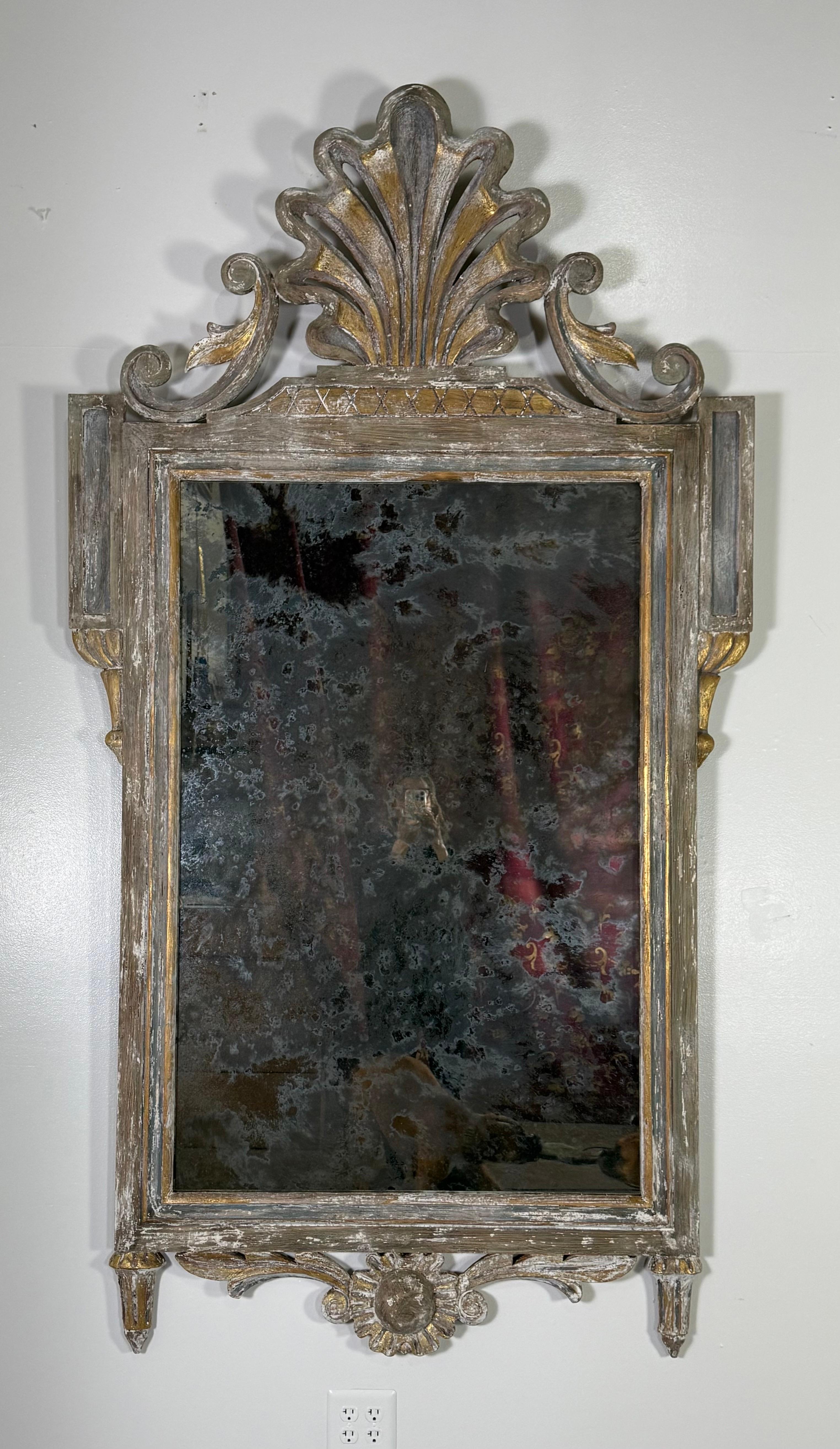 Monumental size French painted Rococo-style mirror.  The frame is ornately carved with intricate detailing.  The top features a decorative crest with an elaborate shell motif, flanked by two scrolling elements adorned with leaf-like carvings.  The