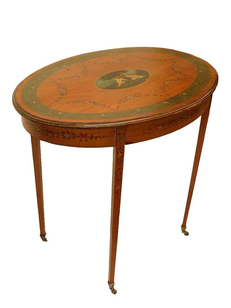 French painted satinwood center table, the top border with flowers and foliate intertwined with stylized ribbon on a verde band, inside this are connected arches of flowers and foliate; central cartouche features two nymphs picking apples from an