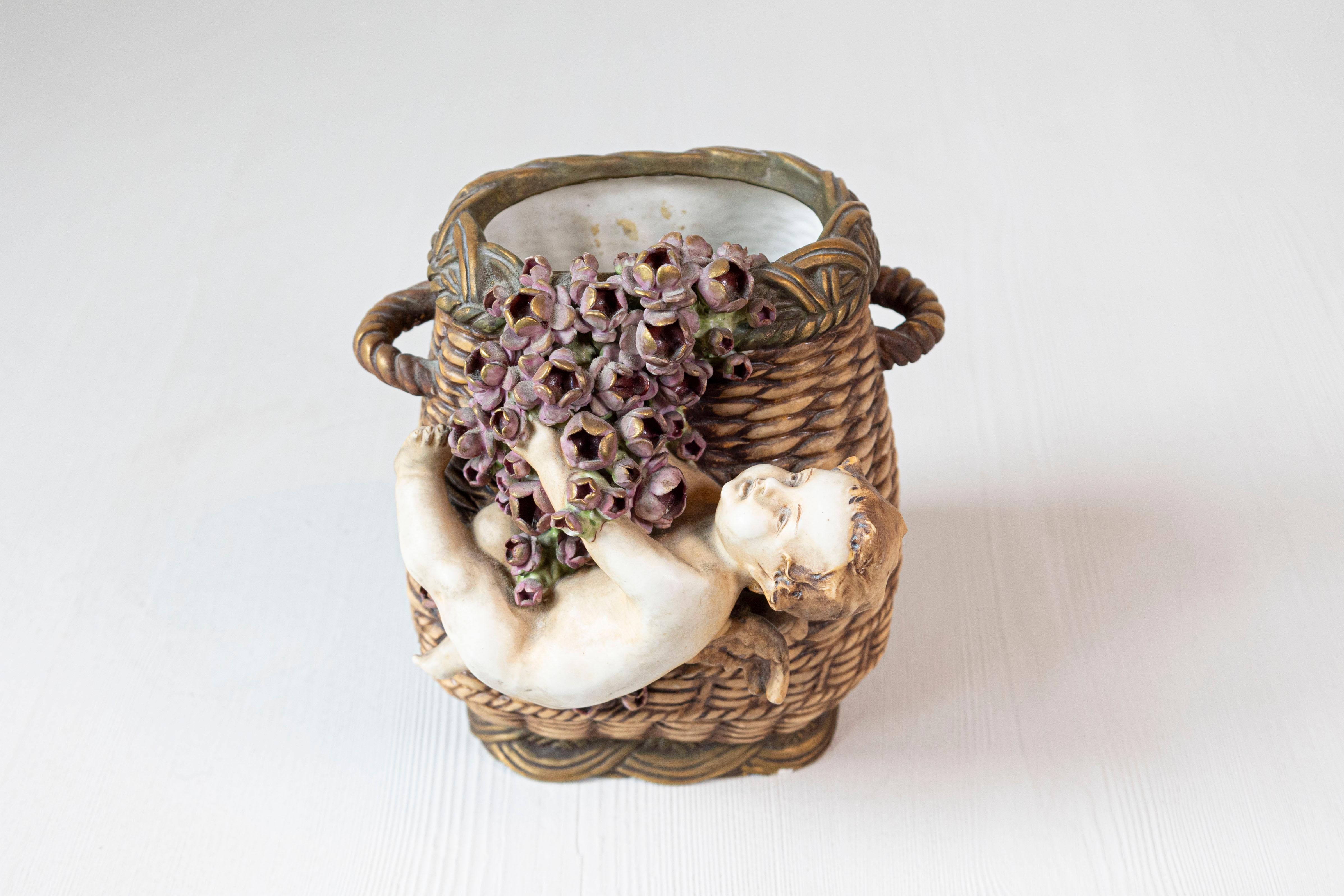 Vaso in terracotta dipinta francese ispirato al vimini della metà del XIX secolo, con cherubino e fiori. Realizzato in Francia nel terzo quarto del XIX secolo, questo vaso in terracotta dipinta presenta un cesto affusolato in vimini a doppio manico